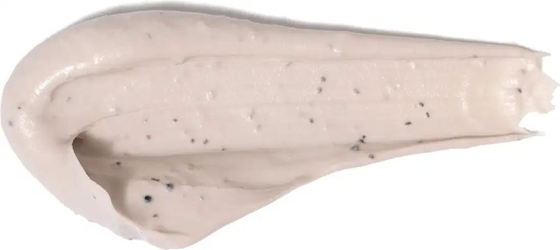 Textura cremosa, brilhante e densa de um item de cuidados com a pele, com pequenos pontos escuros visíveis em sua superfície.