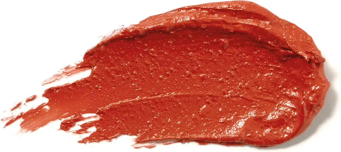 Textura cremosa e brilhante do batom glossy na cor Coral da marca Make B. A aparência é brilhante e leve e está espalhada em superfície branca.