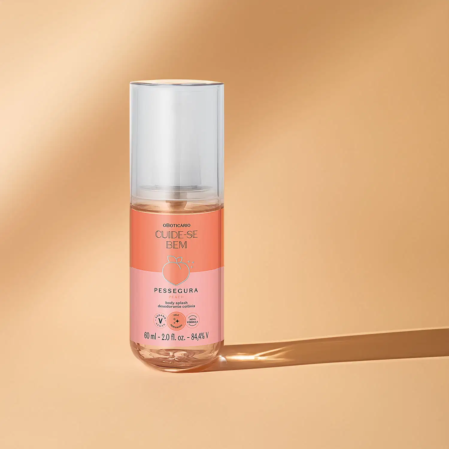 Frasco transparente com líquido rosa, tampa branca e rótulo em tons de rosa com pêssego ilustrando contendo 60ml de body splash Cuide-se Bem Pessegura em fundo rosa com sombras.