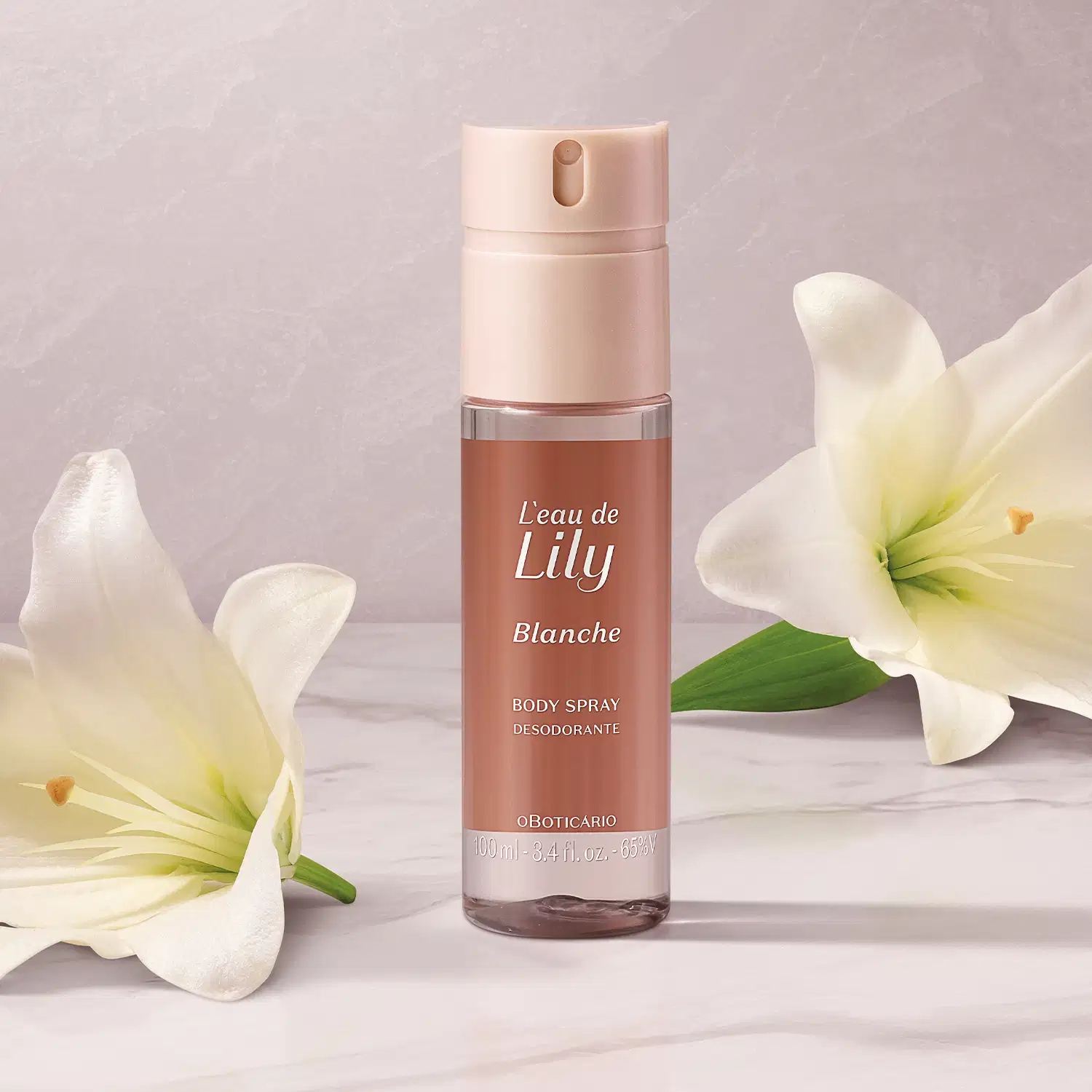 O frasco é de cor rosa claro, com um rótulo que exibe o nome da fragrância em destaque. O produto é apresentado em um recipiente com um aplicador spray. Ao lado do frasco, há flores de lírio brancas, que parecem complementar a imagem do produto.
