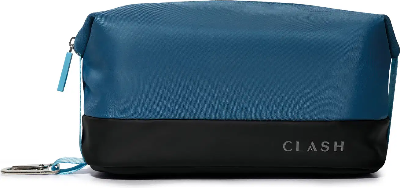 Bolsa de cosméticos azul-marinho com faixa preta na barra, com zíper e alça, exibindo a marca "CLASH" em letras grandes no canto inferior direito.