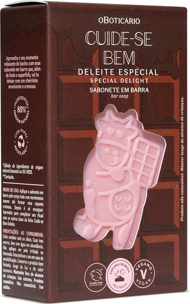 A embalagem apresenta um sabonete em barra na cor rosa claro, com formato de personagem infantil. Contém textos em português e espanhol, como "Cuide-se bem", "Deleite Especial" e "Sabonete em Barra". Também exibe símbolos vegano e não testado em animais.