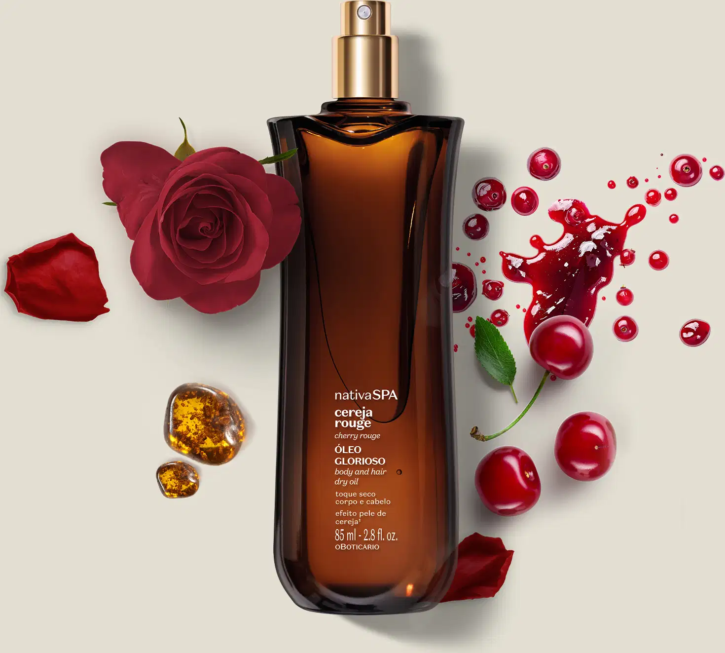 Frasco de vidro vermelho com tampa dourada. Rótulo indica "nativa SPA cereja rouge óleo glorioso ". Acompanhado por rosas vermelhas, cerejas, folhas e pedras âmbar. Embalagem de 85ml. Cores predominantes são vermelho, dourado e âmbar.