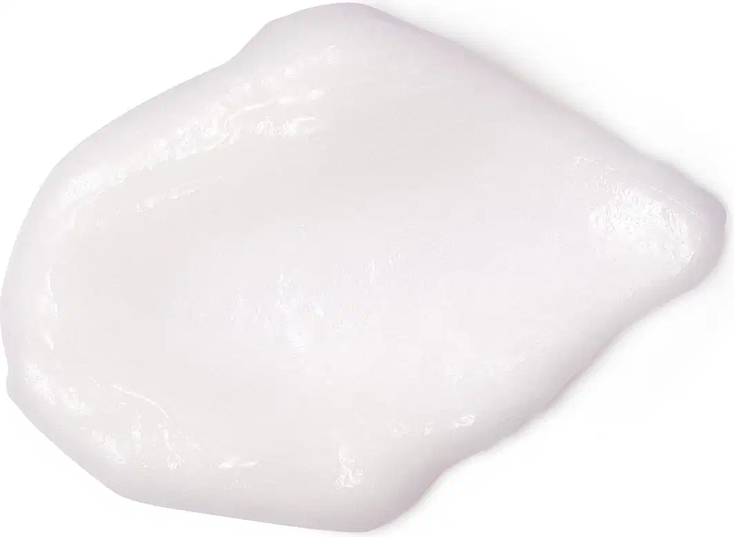Textura branca, brilhante e densa de um item de cuidados com a pele cobrindo boa parte da superfície, também branca.
