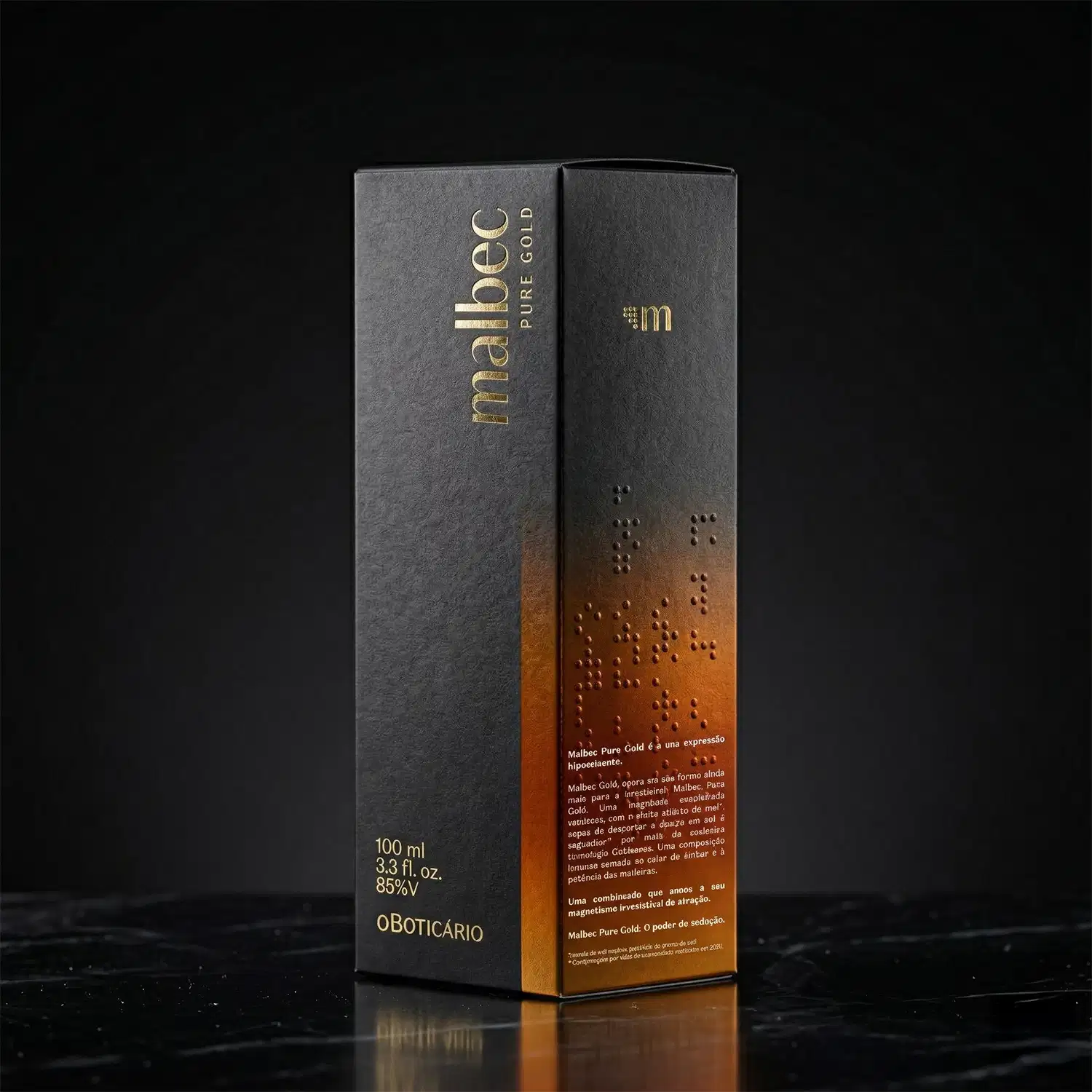 Imagem de caixa vinho e dourada de desodorante colônia Malbec Pure Gold sobre superfície escura refletiva, com texto em relevo e detalhes em dourado.
