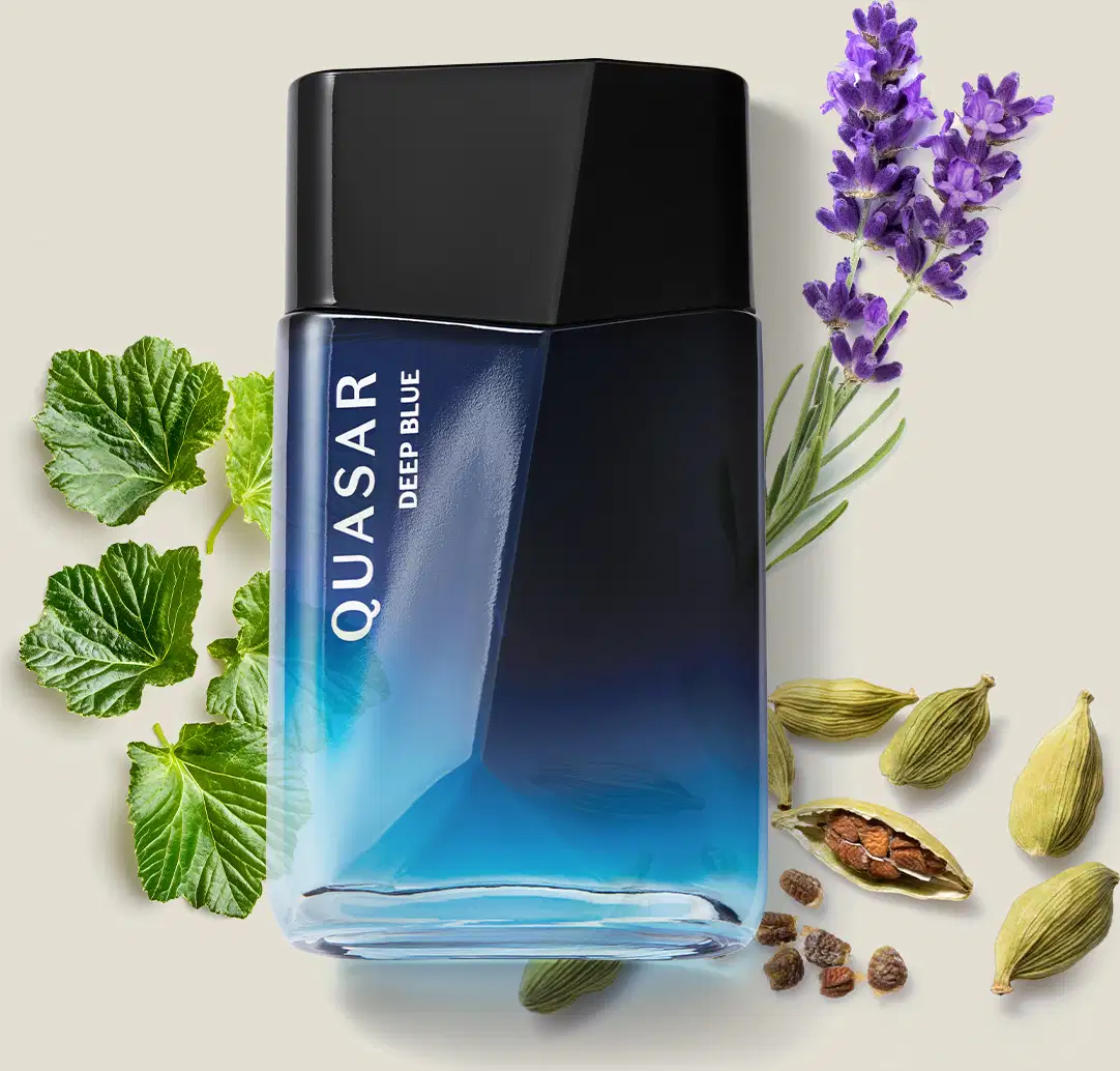 Frasco de desodorante colônia da marca Quasar Deep Blue em embalagem azul, rodeado por folhas verdes, flores roxas e especiarias em um ambiente claro e natural.