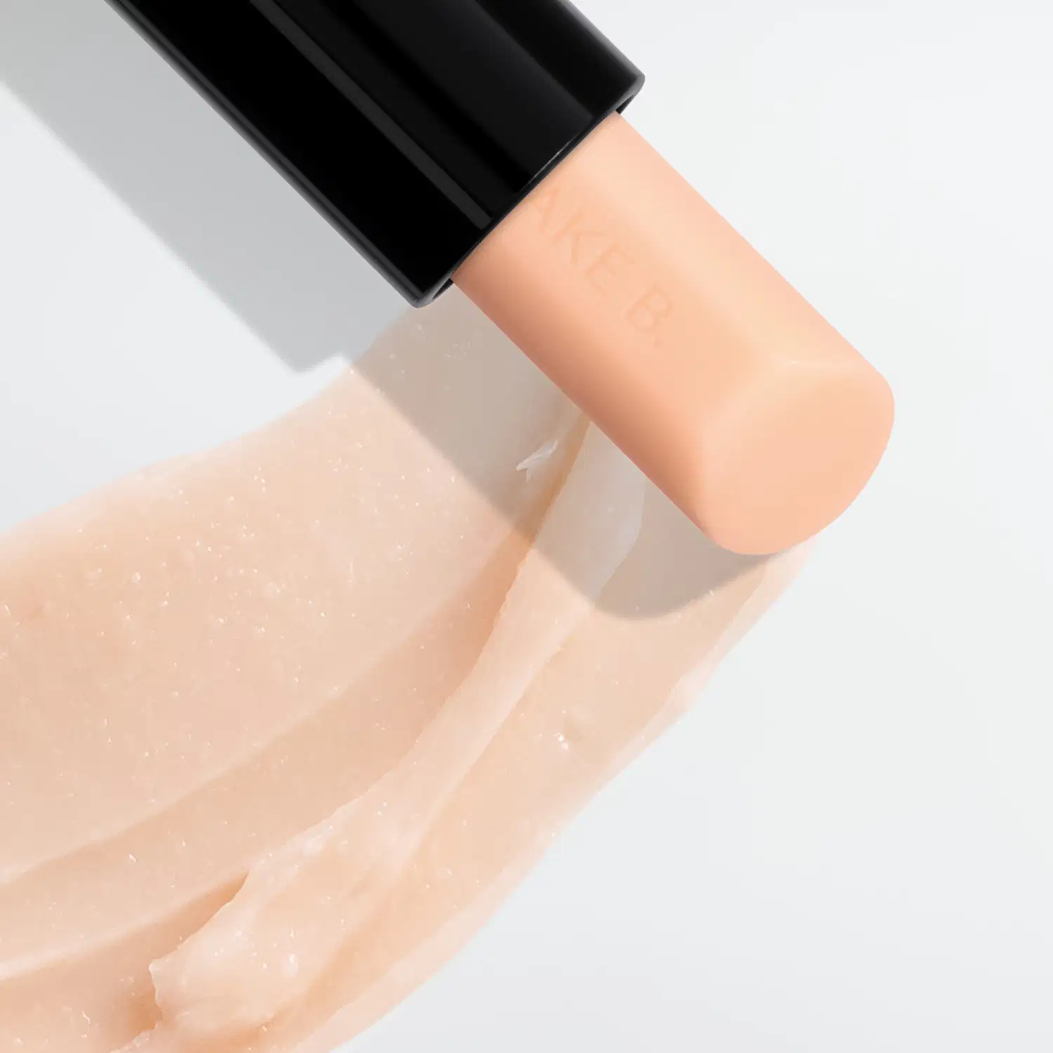 Embalagem de Balm Labial Noturno da marca Make B. Lip Chronology Night Plump em fundo branco, com textura brilhante e translúcida, refletindo a luz.