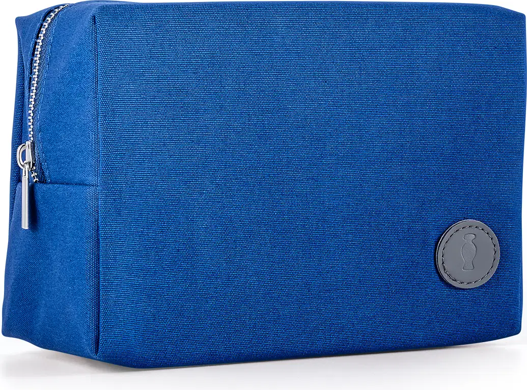 Nécessaire de tecido azul em formato retangular com zíper prateado e detalhe em couro cinza da marca O Boticário.