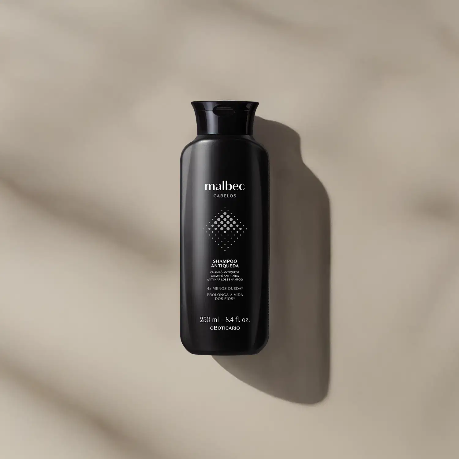 Frasco preto com letras brancas e detalhes cinza contendo 250ml de shampoo antiqueda Malbec Cabelos em fundo bege com sombras.