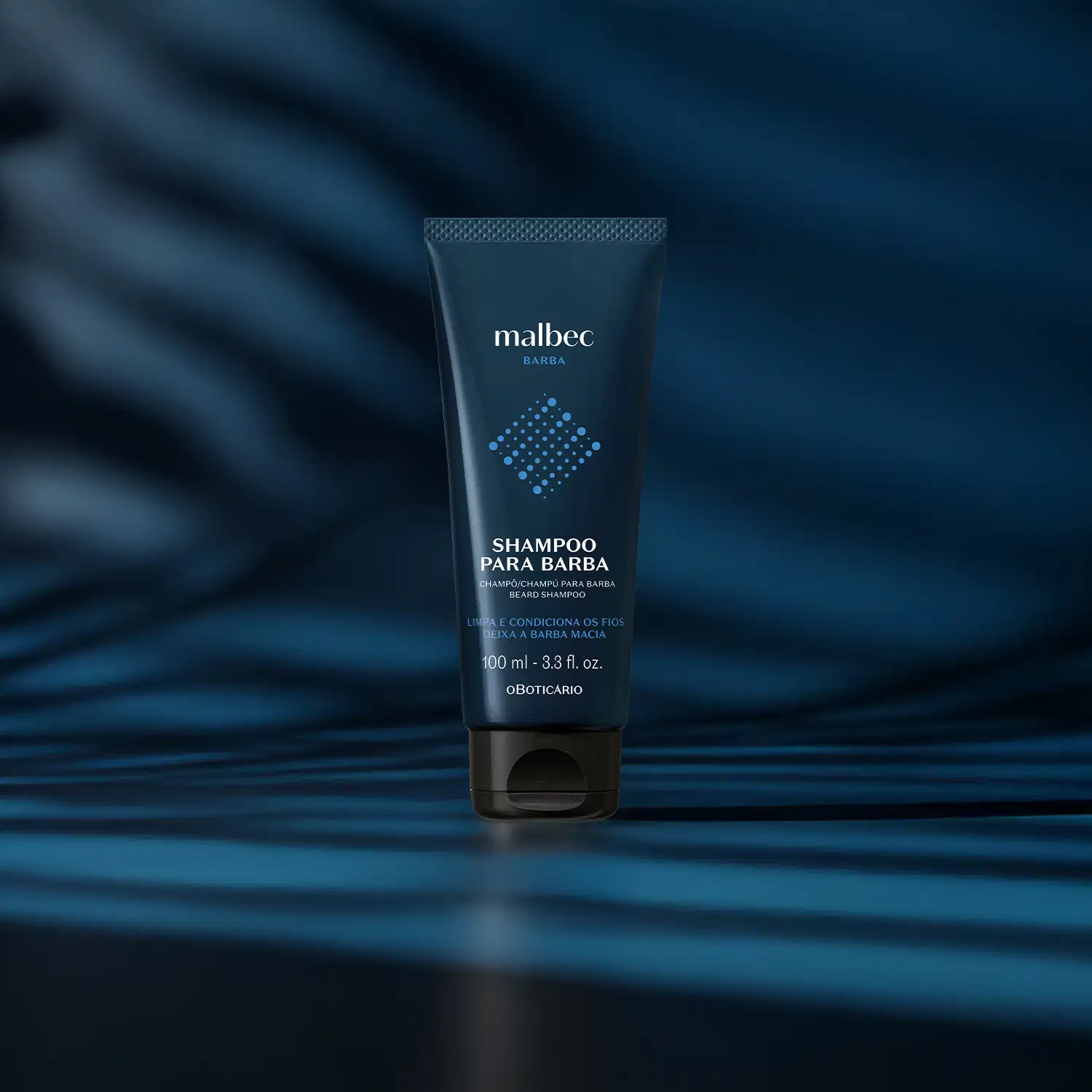 Bisnaga azul escura com letras brancas e detalhes em outro tom de azul contendo 100ml de shampoo para barba Malbec Barba em fundo escuro com luzes azuis.