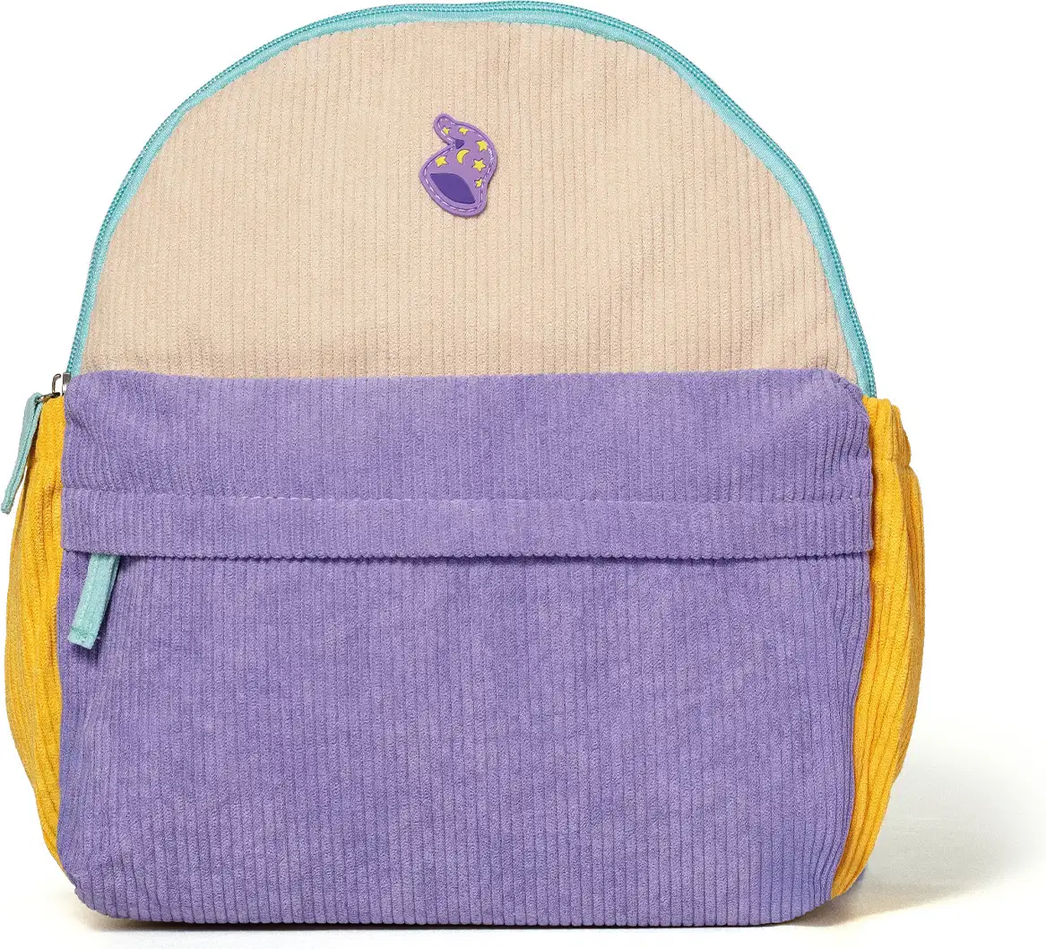 Mochila infantil de veludo canelado nas cores bege, lilás e amarelo, com zíper e aplicação de ícone em formato de touca de mago na parte frontal. Vista de frente.