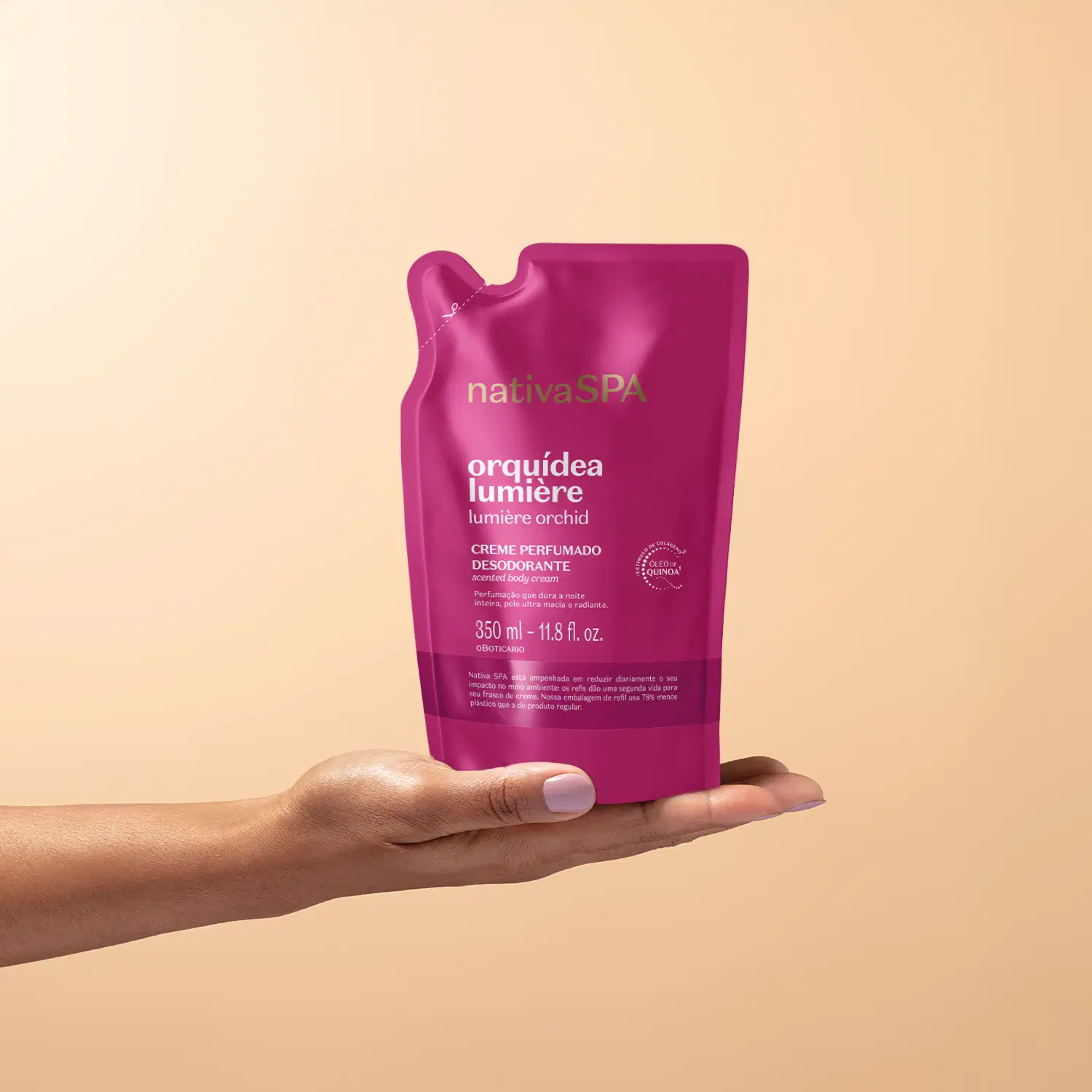 Embalagem flexível contendo refil de creme perfumado desodorante da marca Nativa SPA Orquídea Lumière, na cor rosa vibrante posicionada sobre uma mão feminina espalmada em fundo na cor salmão.