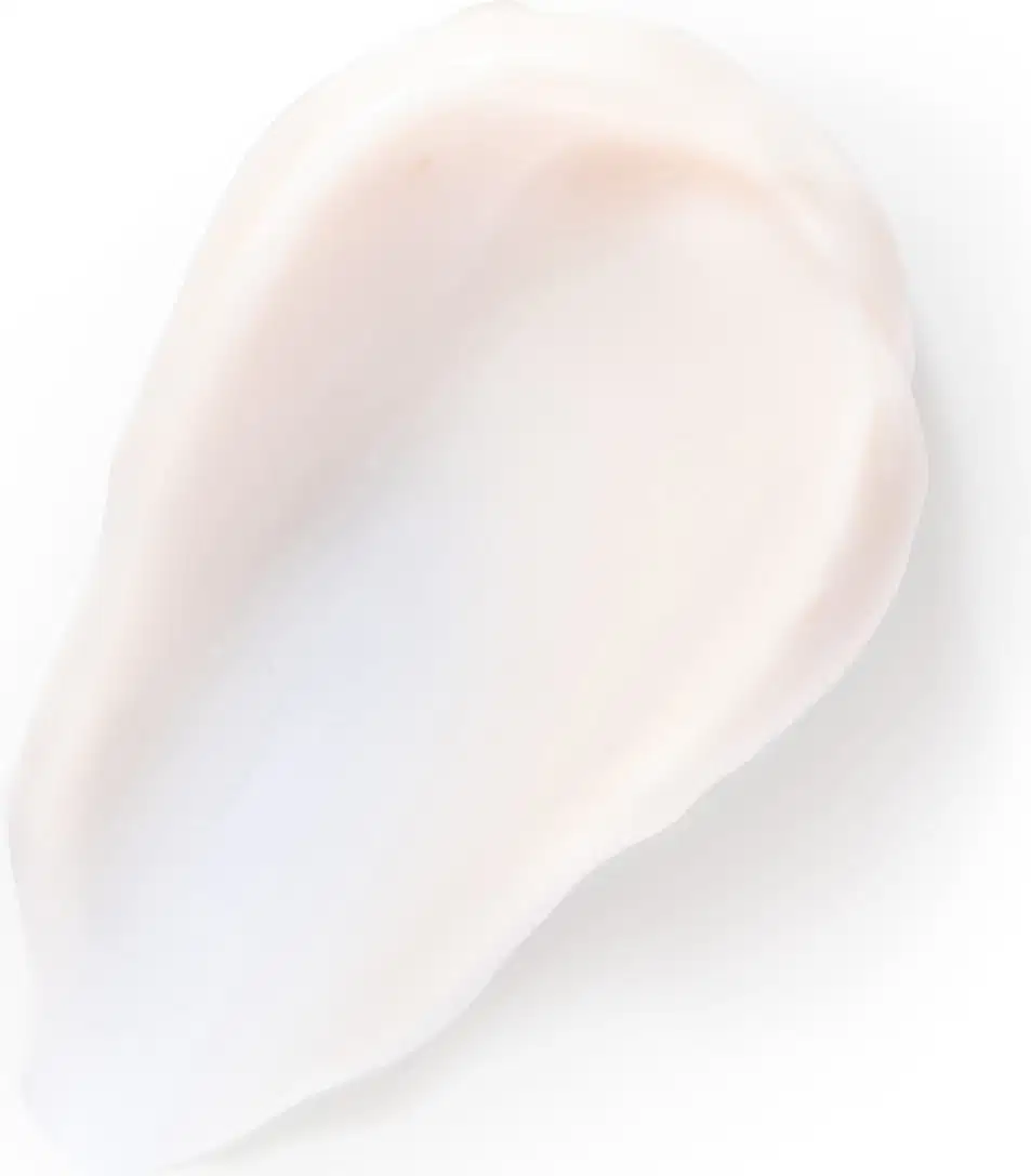 Textura cremosa e brilhante de um item de corpo e banho na cor branca, espalhado sobre superfície clara.