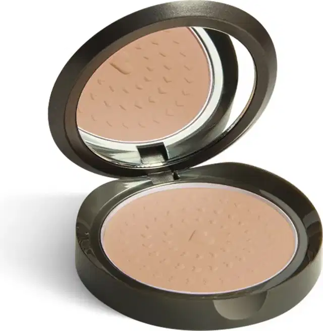 Estojo de pó compacto facial com embalagem redonda na cor verde musgo escuro. O estojo está aberto, mostrando o produto na base e um espelho na tampa, que reflete parcialmente o produto.