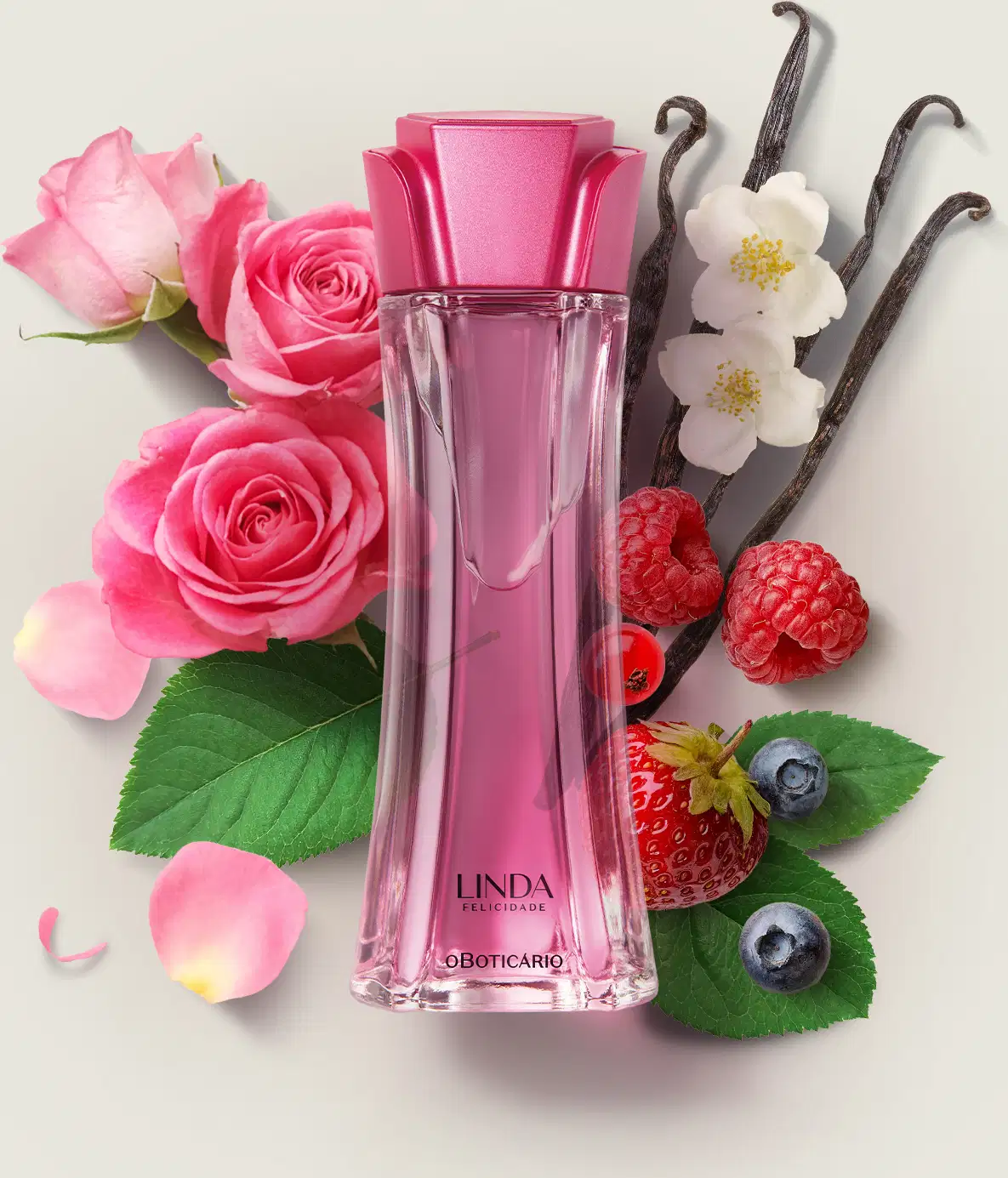 Frasco de vidro com líquido rosa e tampa rosa em formato de flor contendo desodorante colônia Linda Felicidade em meio a rosas, framboesas, baunilha e flores brancas sobre superfície clara.