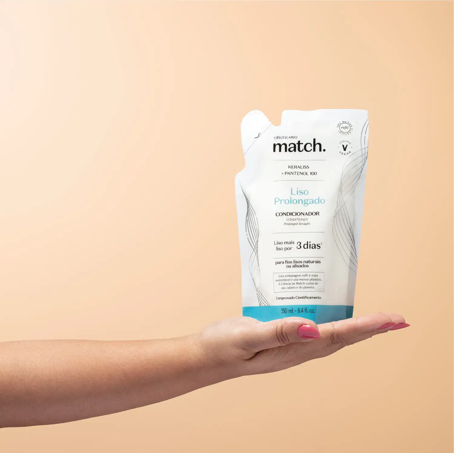 Mão segurando um refil de condicionador Match Liso Prolongado em sachê nas cores azul e branca com letras pretas em fundo em tons de rosa.