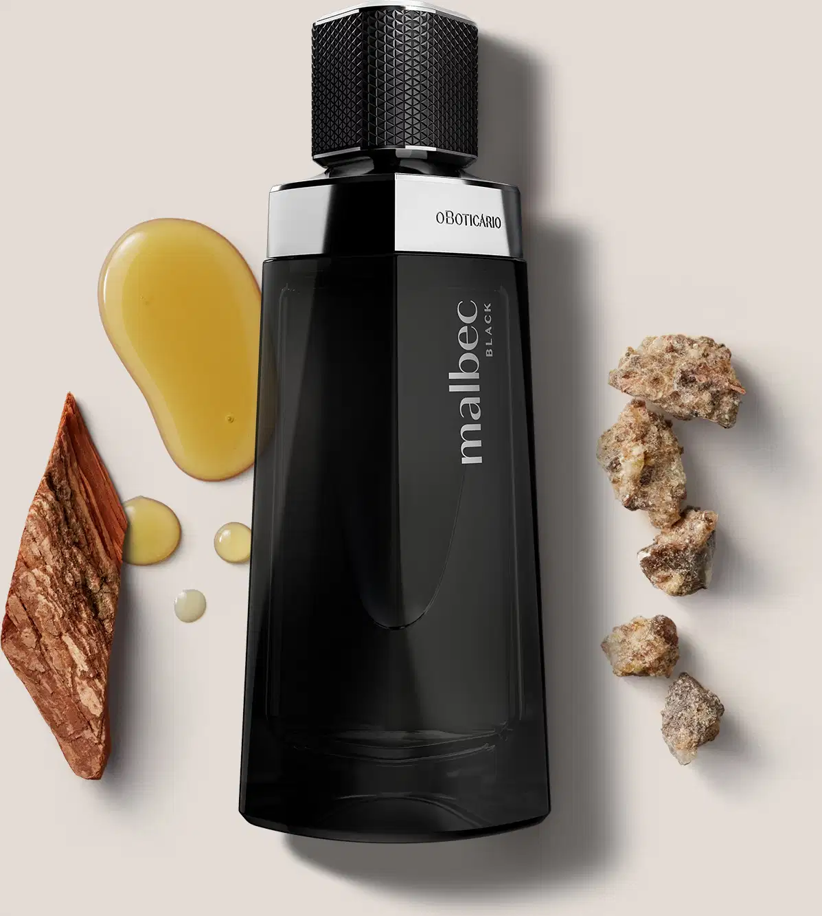 O frasco é preto e possui um design moderno e elegante. Ao redor do frasco, há alguns elementos decorativos, como pedras, madeiras e uma substância líquida amarelada, que parecem ser ingredientes naturais utilizados na composição da fragrância.