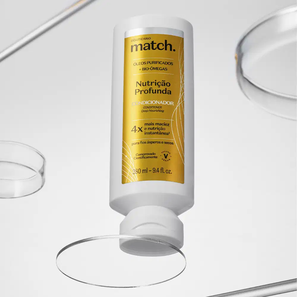 Imagem de um frasco branco do Condicionador Match Fonte da Nutrição contendo rótulo laranja com detalhe prateado e informações impressas em letras amarelas e pretas. Ao redor do item, estão espalhados alguns círculos de vidro transparentes.