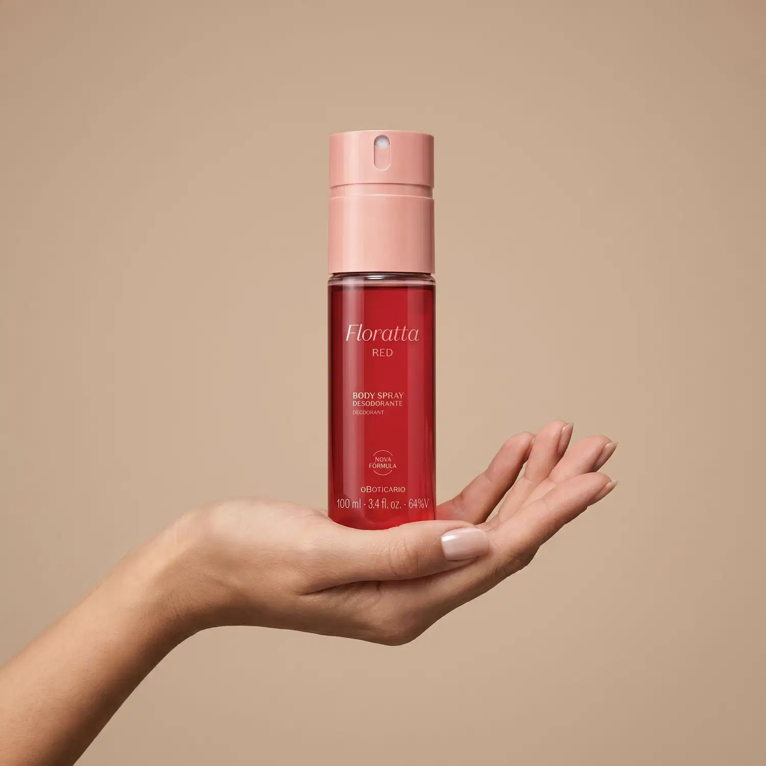 Embalagem vermelha de item de perfumaria Floratta Rede sobre mão feminina espalmada sobre fundo rosado.