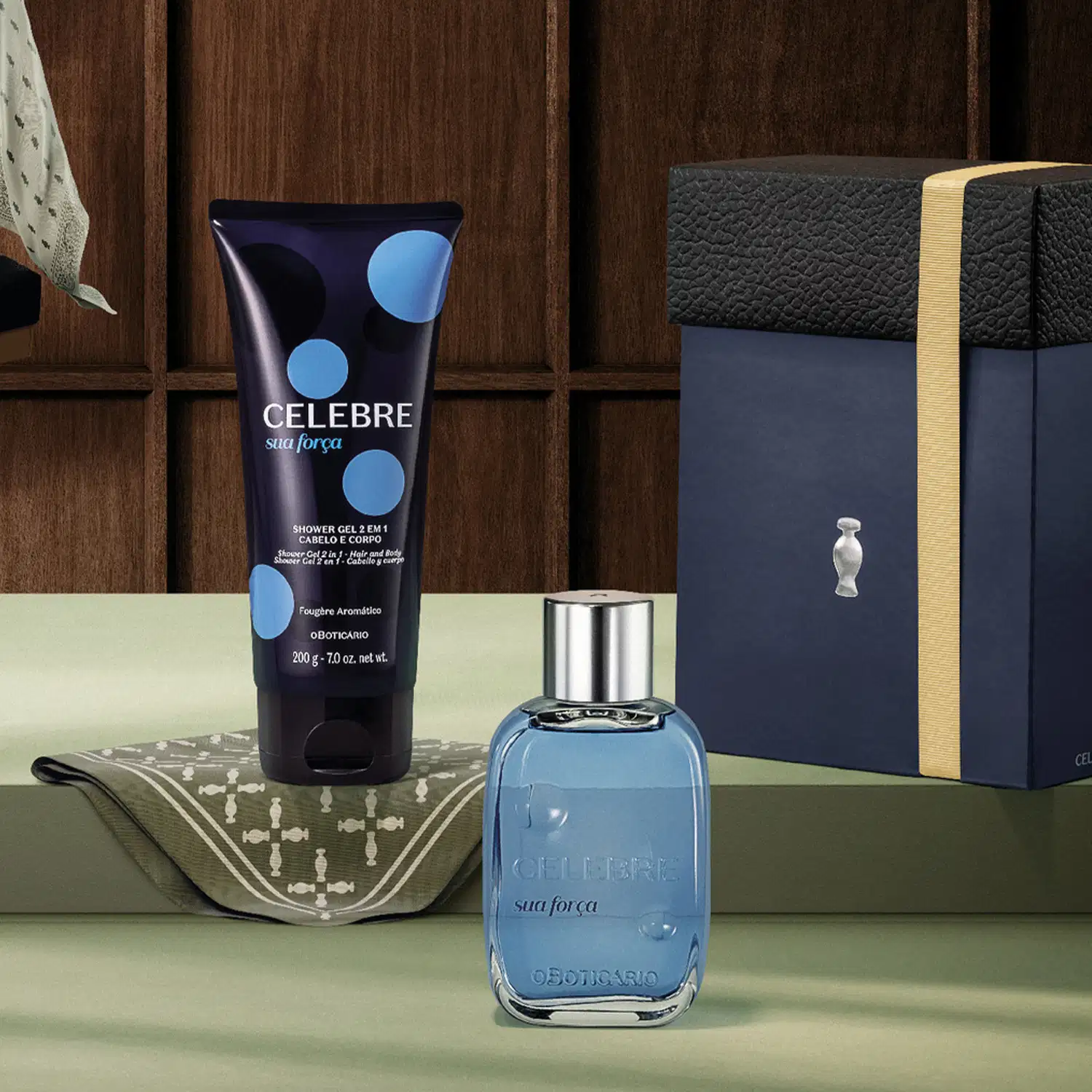 Ambiente de banheiro com produtos da marca Celebre, incluindo um frasco de fragrância e um gel de banho em embalagem azul e preta, sobre um fundo de madeira escura e tecido estampado.