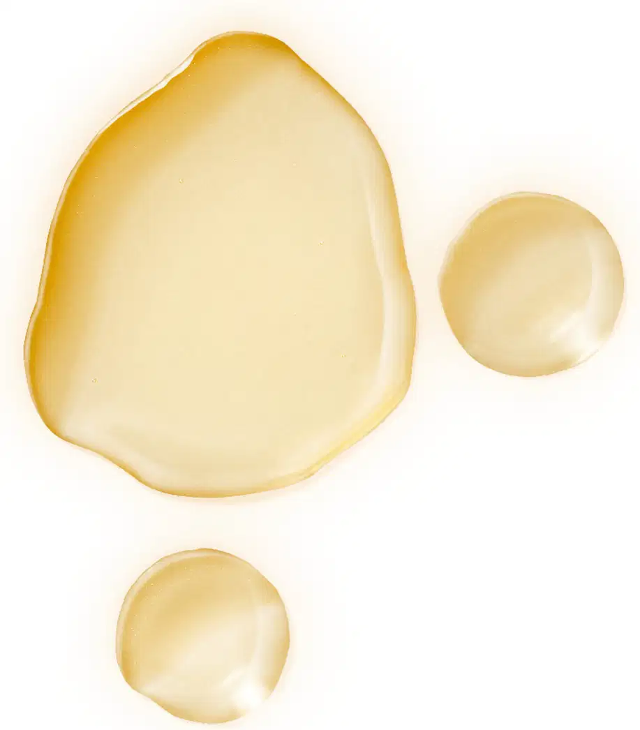 Textura viscosa e brilhante de tom amarelo claro, formando três círculos irregulares de tamanhos distintos sobre superfície plana e branca.