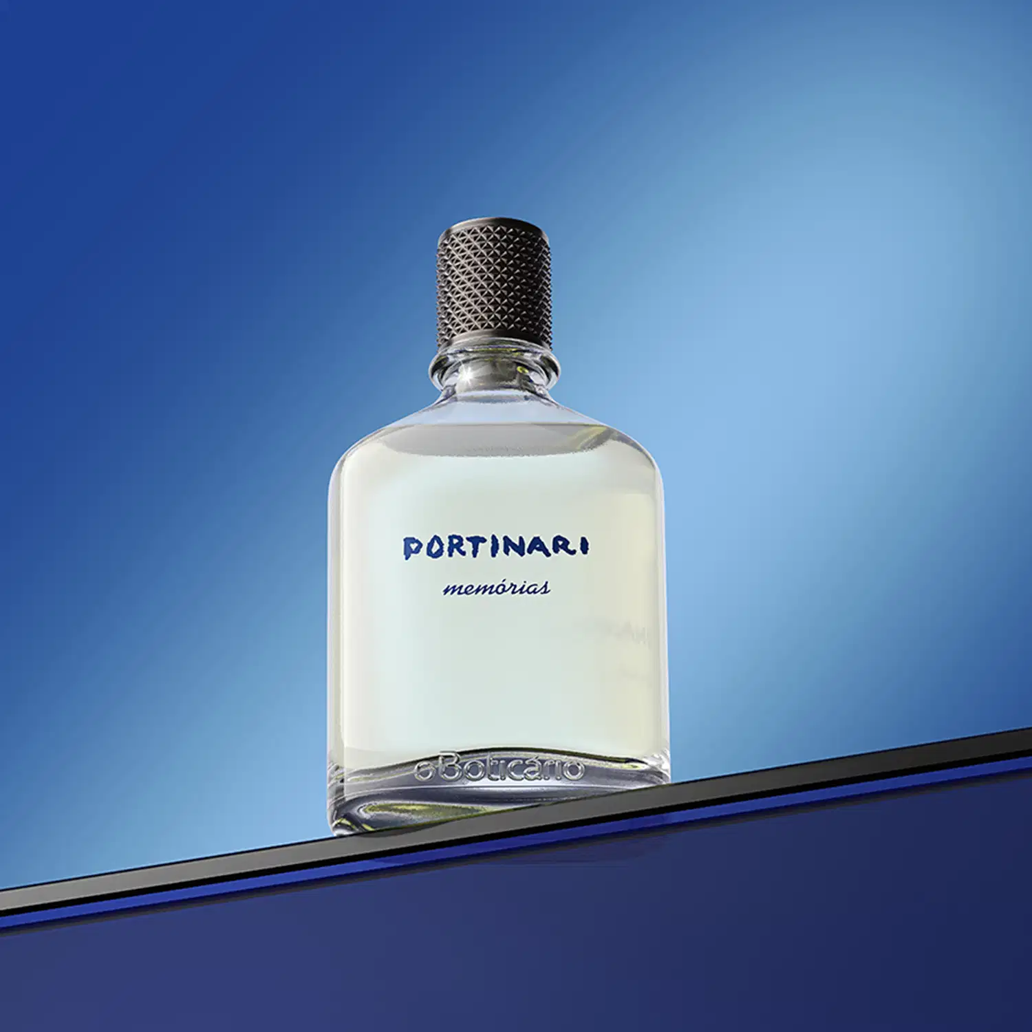 Frasco de vidro transparente com a marca Portinari Memórias gravado em azul escuro, com tampa preta texturizada em formato geométrico sobre superfície azul, com fundo azul claro, visto de baixo para cima..