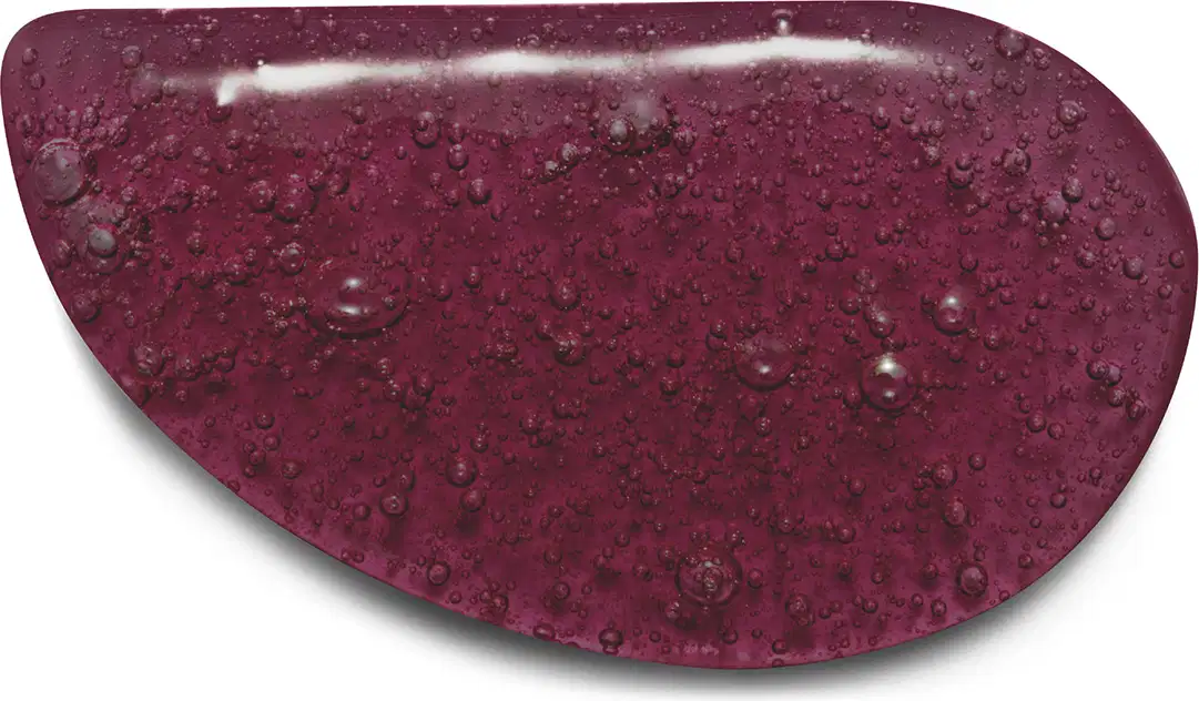 A imagem mostra a textura do sabonete líquido Nativa SPA Ameixa Negra com pequenas bolhas e gotas, em tom de vinho tinto, com aspecto úmido e brilhante.