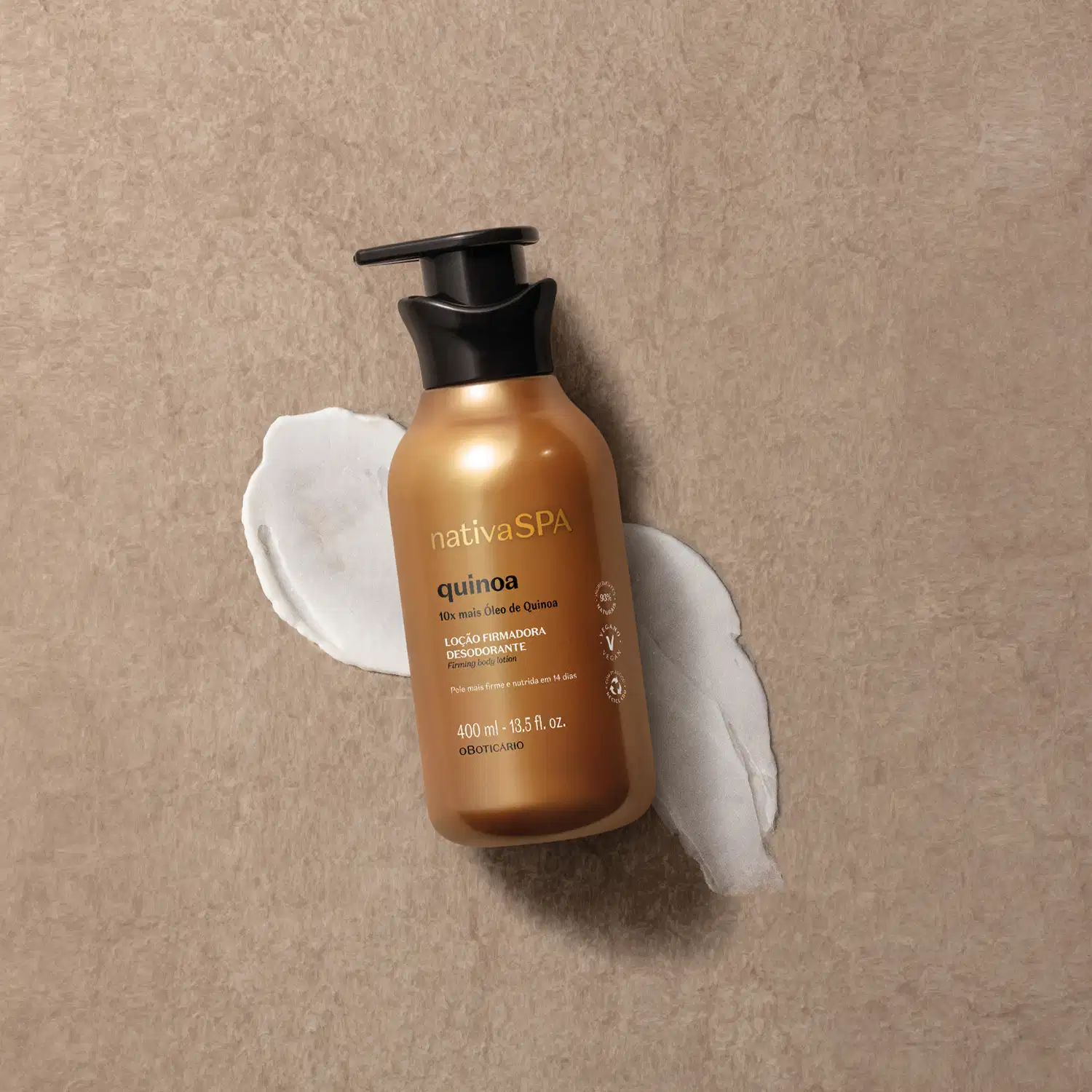 Imagem de um frasco de loção firmadora corporal da marca Nativa SPA Quinoa, com embalagem dourada e tampa preta. Ela está sobre superfície bege com um pouco de creme espalhado embaixo do frasco.
