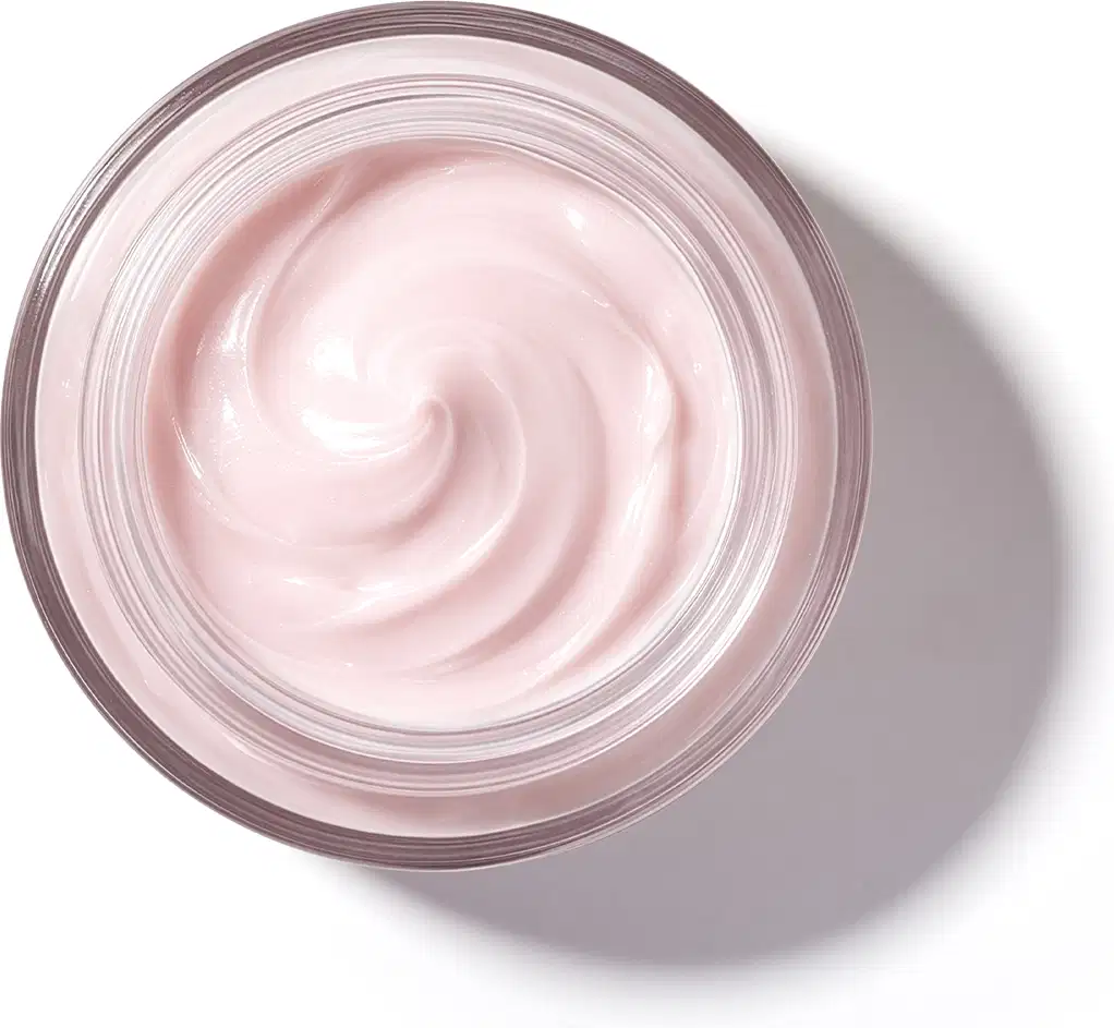 Pote de vidro visto de cima com foco na textura do creme com padrão de espiral suave de textura cremosa e brilhante em tom de rosa claro.