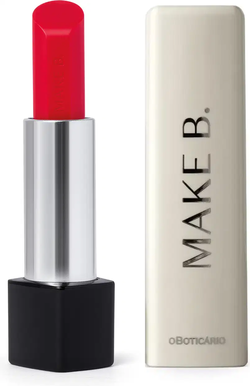 O balm labial vermelho da marca Make B. Lip Chronology Color Repair possui uma embalagem preta e prateada com produto  vermelho brilhante e tampa branca com a marca gravada em letras pretas.
