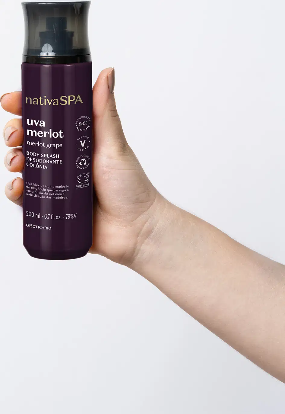 Mão segurando um frasco preto e roxo com letras brancas e douradas contendo loção hidratante corporal Nativa SPA Uva Merlot.