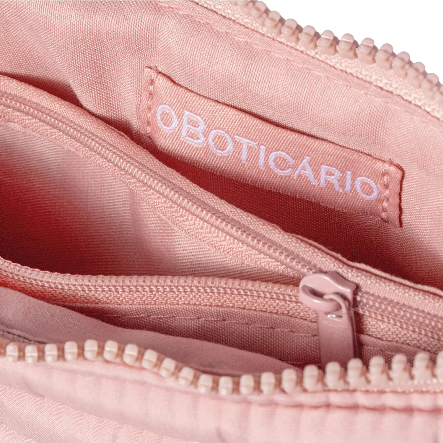 Close-up da parte interna do nécessaire, enfatizando a presença de um bolso interno rosa-claro com zíper e etiqueta com a marca O Boticário costurada.