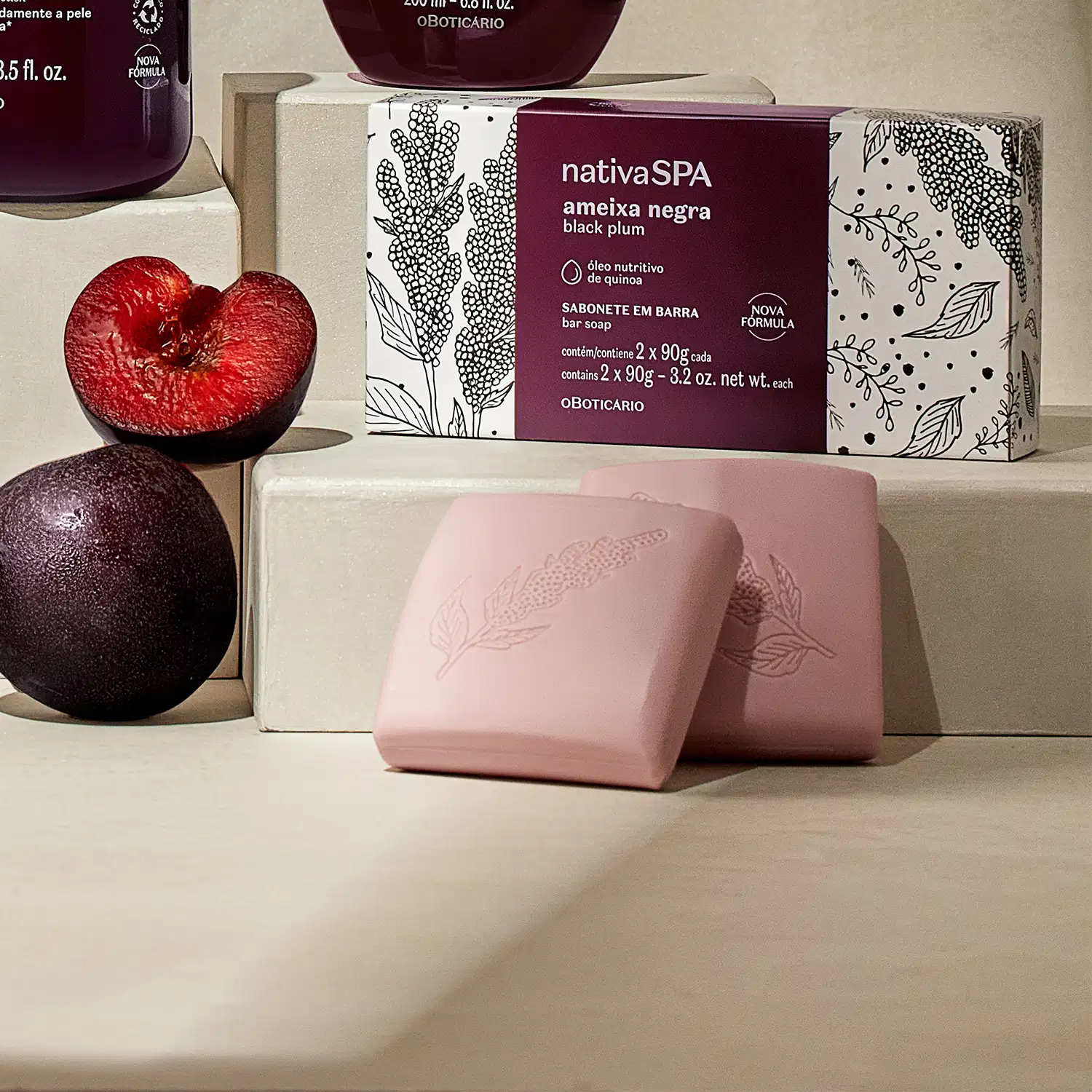 Caixa e dois sabonetes em barra da marca Nativa SPA Ameixa Negra, csobre superfície clara, acompanhada de frutas vermelhas e roxas, em ambiente minimalista e monocromático.