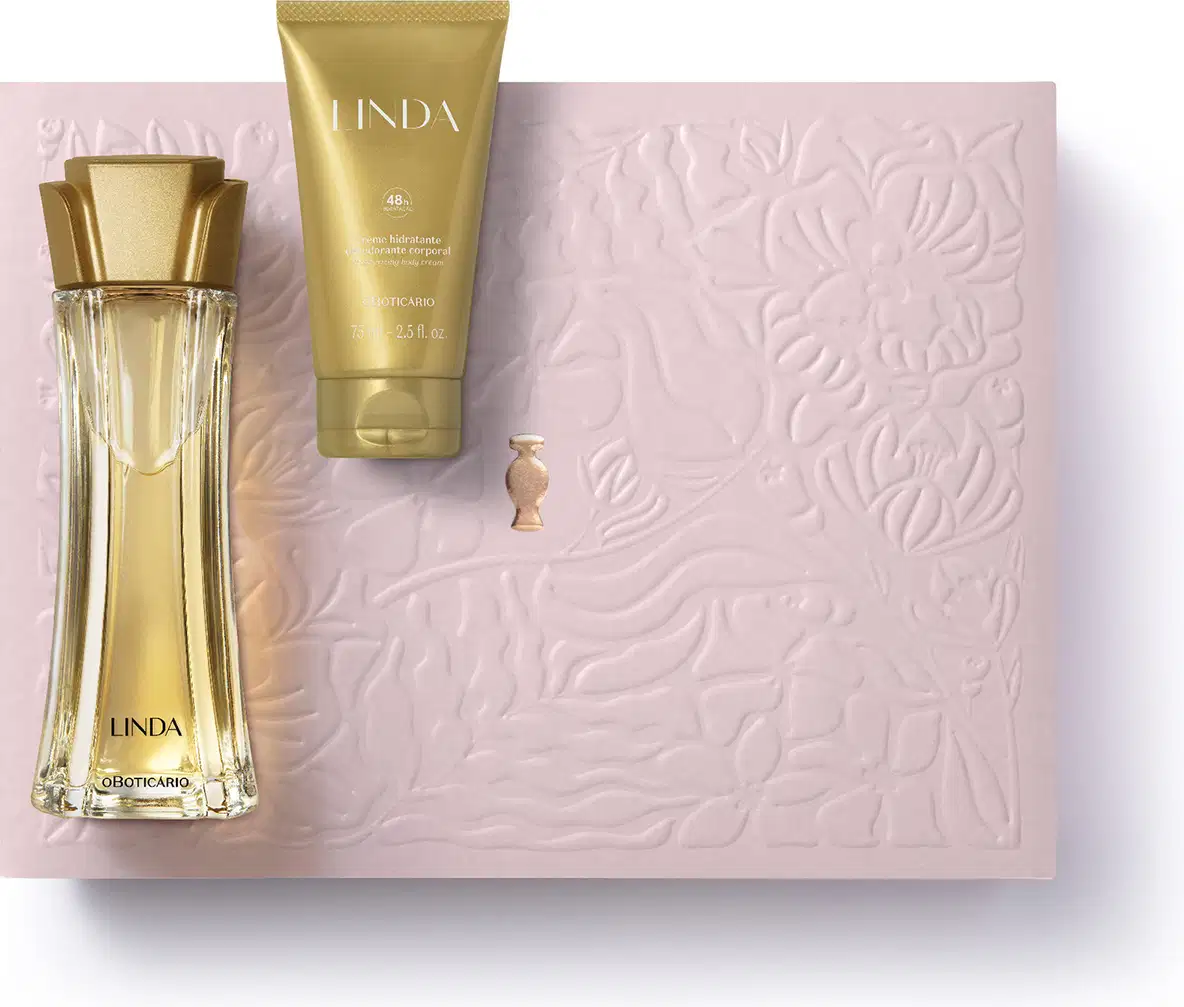 Caixa rosa com floral em relevo, nécessaire rosa e dois produtos da marca Linda: frasco de creme hidratante corporal na cor laranja e vidro curvilíneo com líquido alaranjado e tampa laranja de desodorante colônia.