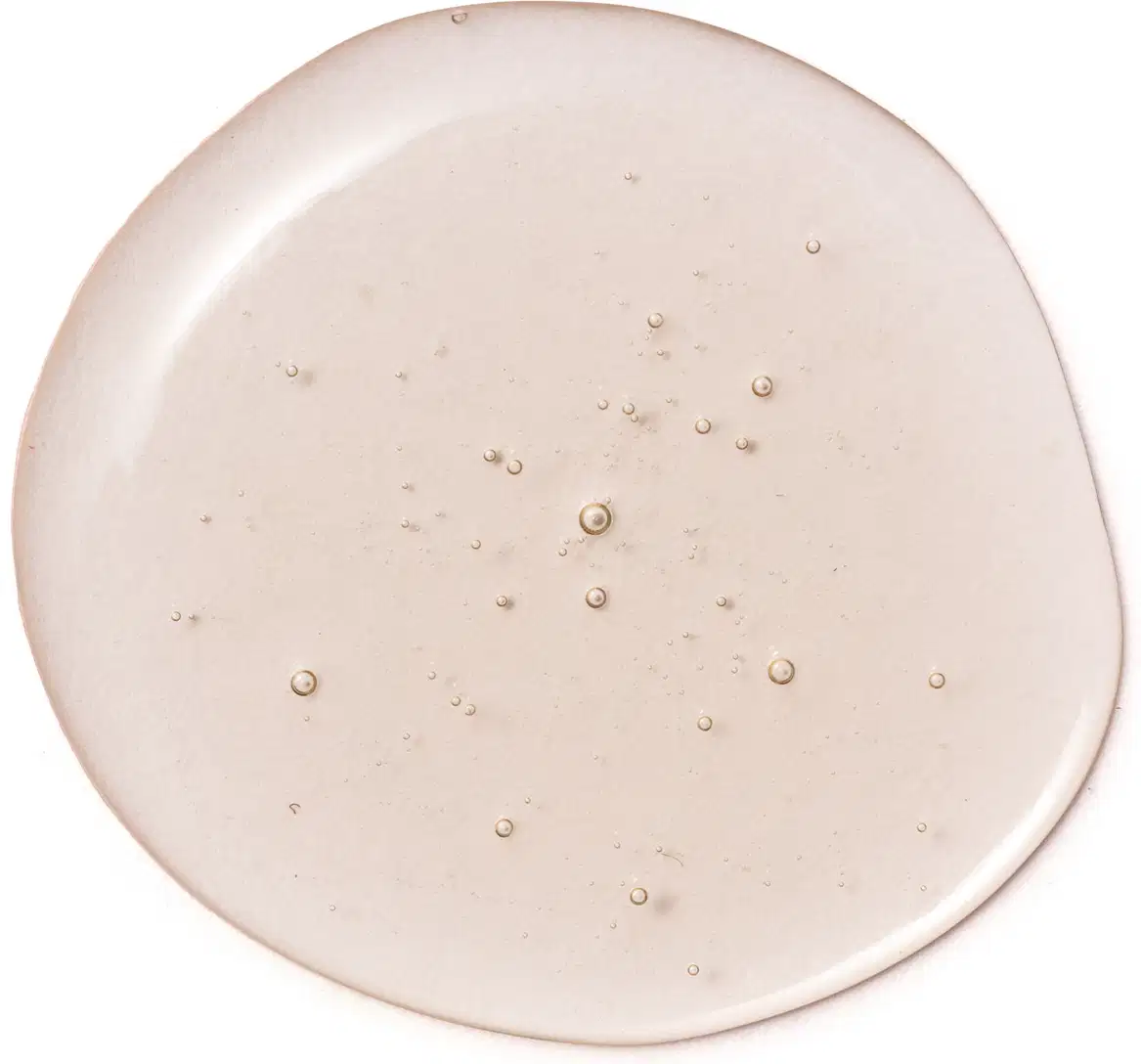 Imagem da textura do gel de limpeza Botik Vitamina C em tom bege claro, com pequenas bolhas e pontos brilhantes, em superfície lisa e levemente úmida.