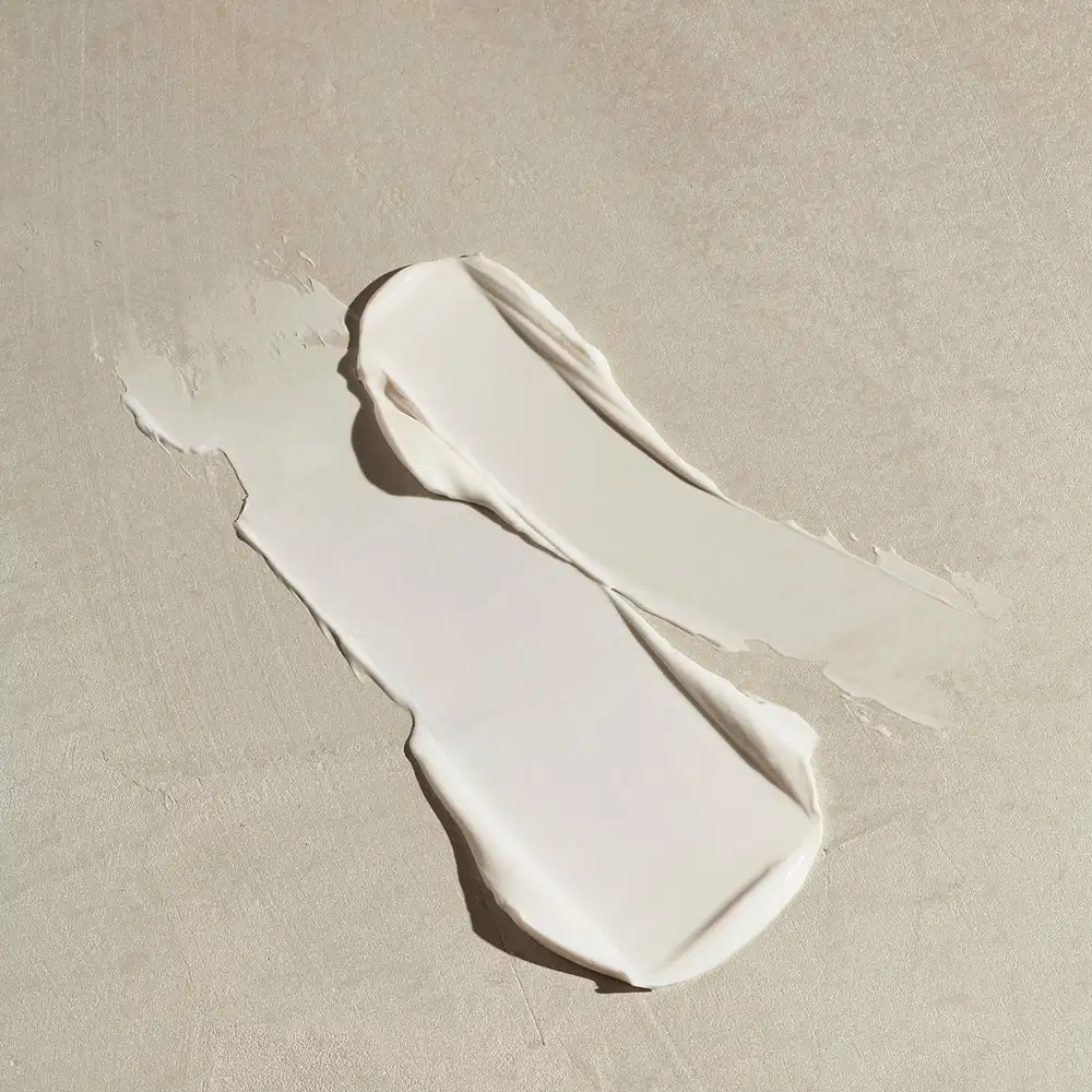 Imagem da textura branca e cremosa de creme hidratante para as mãos Nativa spa Quinoa, com superfície lisa e brilho suave, sobre fundo neutro.