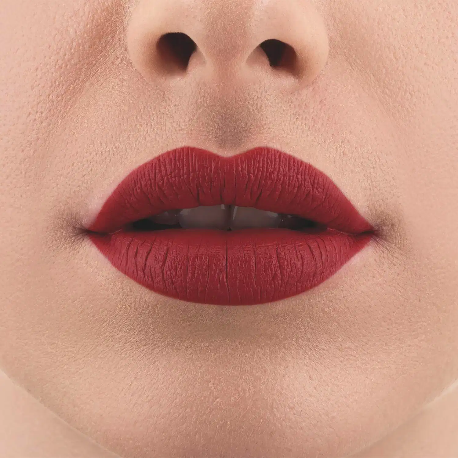 Imagem de um rosto feminino em close-up, evidenciando os lábios com o batom líquido Make B. na cor vermelho intenso. A boca está entreaberta mostrando parcialmente os dentes brancos.