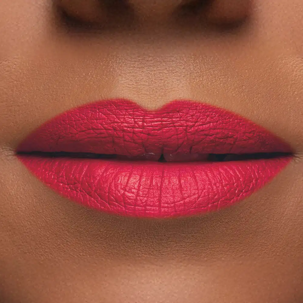 Imagem de um rosto feminino em close-up, evidenciando os lábios com o batom líquido Make B. em tom rosado. A boca está fechada com um leve sorriso.