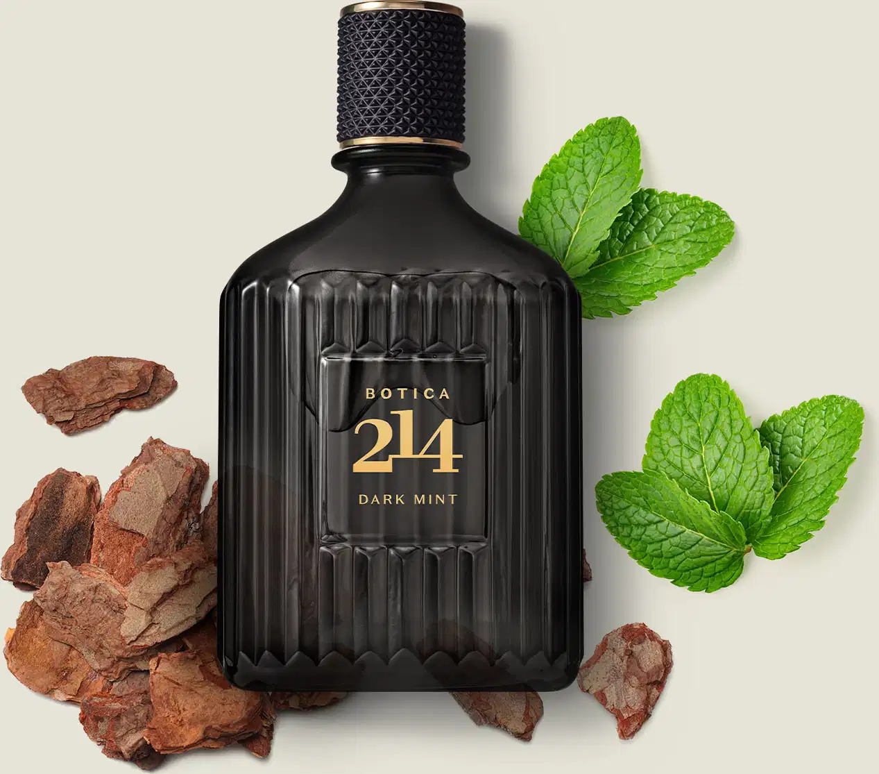 Frasco de vidro preto canelado com rótulo dourado e tampa texturizada de eau de parfum da marca Botica 214 Dark Mint cercado por lascas de madeira e folhas de menta sobre fundo claro.