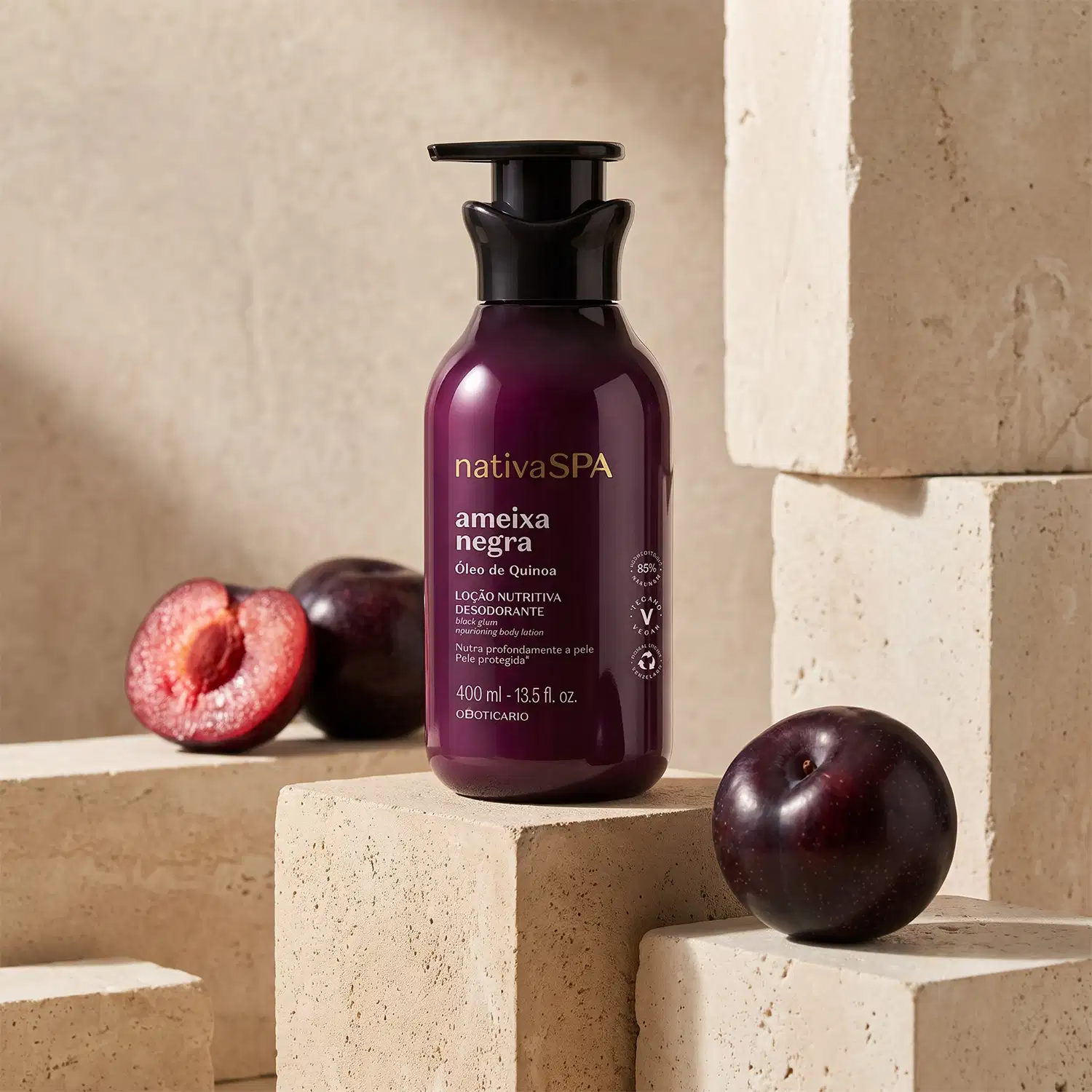 Frasco de loção corporal da marca Nativa SPA, com rótulo roxo, sobre superfície de concreto com ameixas roxas ao redor.