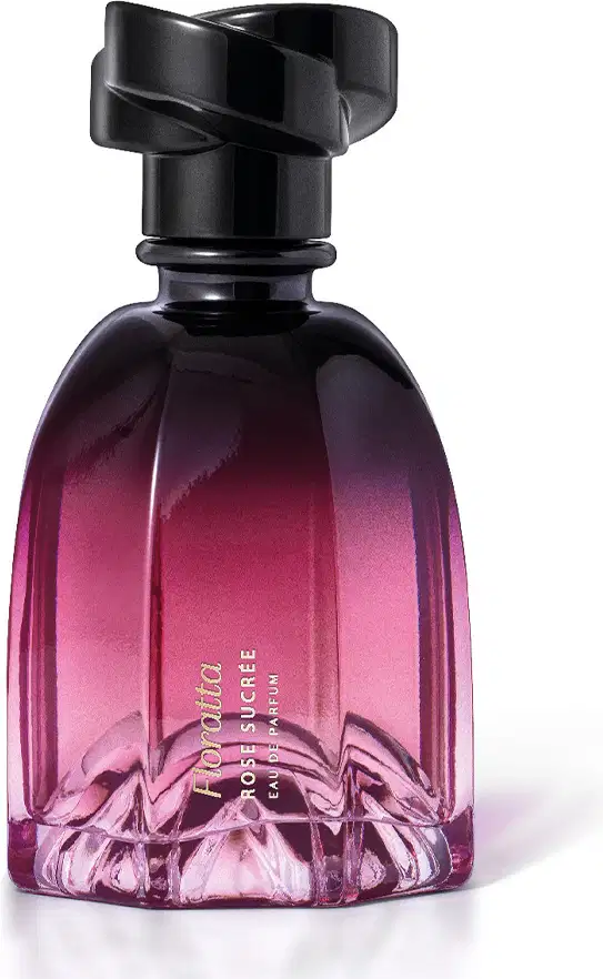 Frasco de perfume Floratta em formato arredondado, com tampa preta e gradiente de cor rosa a roxo. O rótulo exibe o nome da marca em destaque.