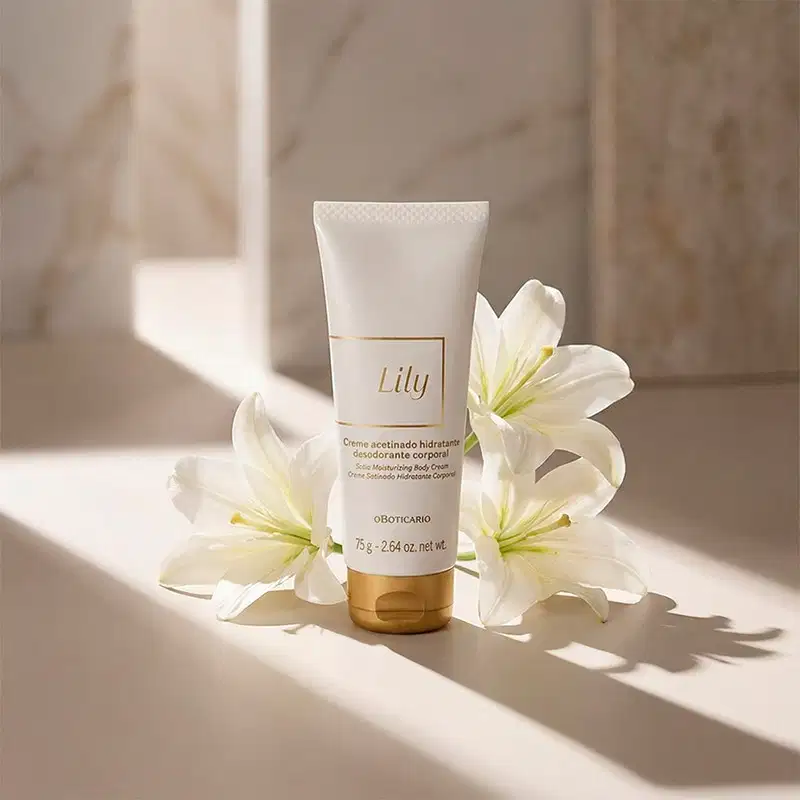 Imagem da bisnaga branca com rótulo dourado da marca Lily, sobre superfície clara e sombreada, com flores brancas ao redor, em ambiente iluminado e minimalista.