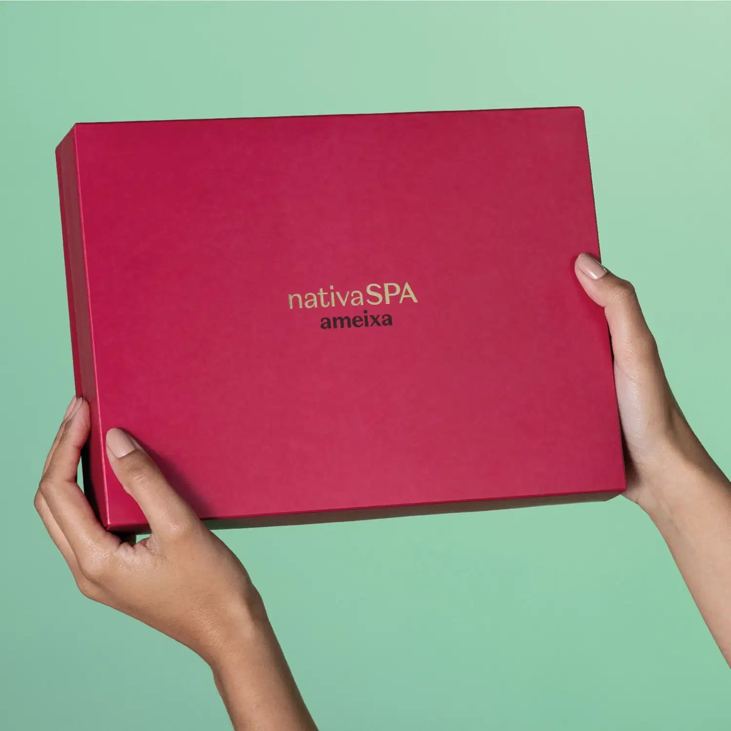 Imagem de uma caixa rosa vibrante com logotipo da marca Nativa SPAA meixa sendo segurada por mãos em fundo verde claro, sugerindo um ambiente  minimalista e neutro.