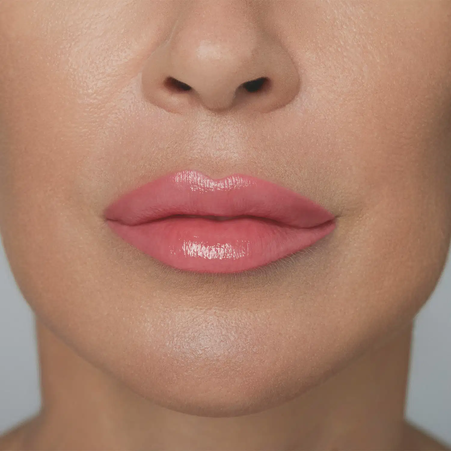 A imagem mostra parte de um rosto feminino em primeiro plano, dando destaque aos lábios, mostrando como o batom rosa da /Make B. fica na pele branca. O fundo é branco e liso.