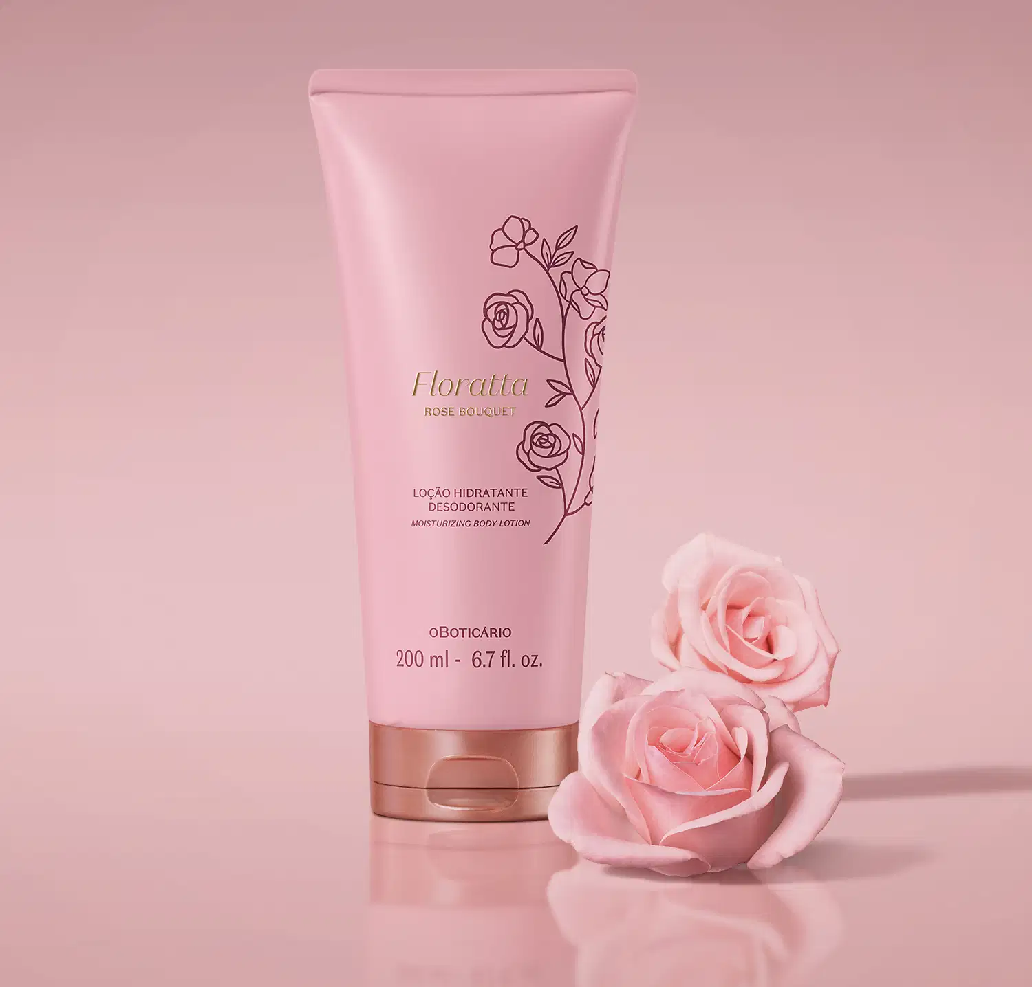Bisnaga rosa com tampa dourada e ilustrações florais de Loção Hidratante Desodorante Floratta Rose Bouquet em cenário todo cor-de-rosa com duas rosas cor-de-rosa desabrochadas posicionadas ao lado da embalagem.
