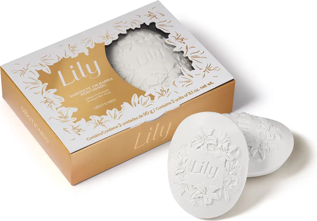 Imagem de uma caixa branca com detalhes dourados contendo dois sabonetes em barra perfumados com 90g cada um da marca Lily. Ao lado da caixa, dois sabonetes brancos em formato oval com flores, folhagens e o nome da marca gravados  no produto.