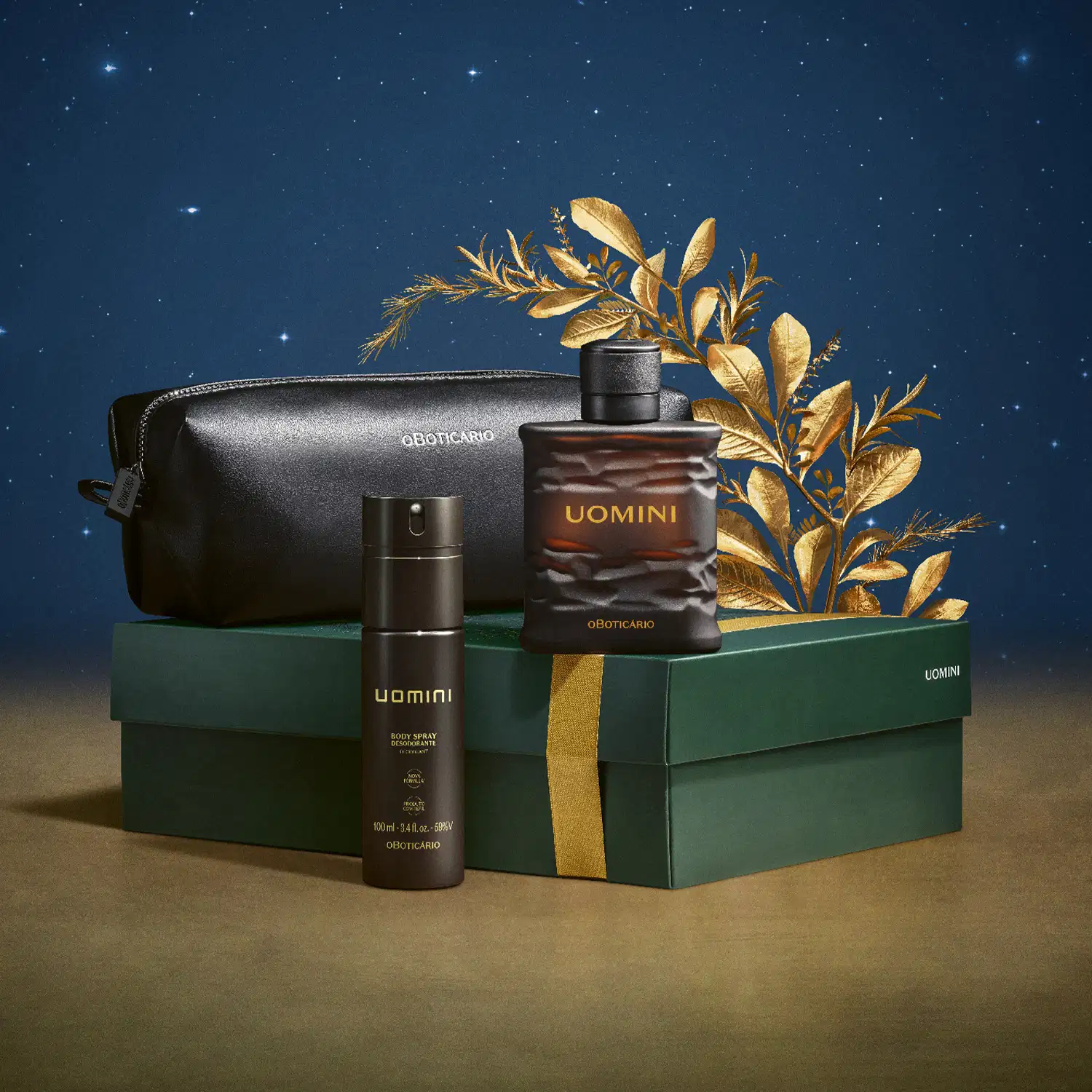 Imagem do Kit Presente Natal Uomini, onde o frasco marrom de desodorante colônia, o body spray e o nécessaire preto estão organizados sobre uma caixa presenteável verde com estampa natalina. A cena traz uma superfície marrom, fundo azul e cipestre dourado