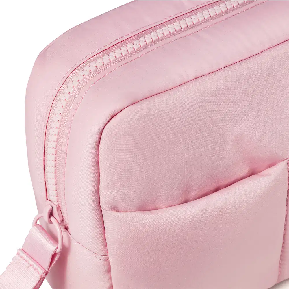 Imagem de uma nécessaire rosa clara com puxador. A bolsa tem vários compartimentos e um zíper na parte frontal. Não há nenhum texto ou rótulo visível na imagem.