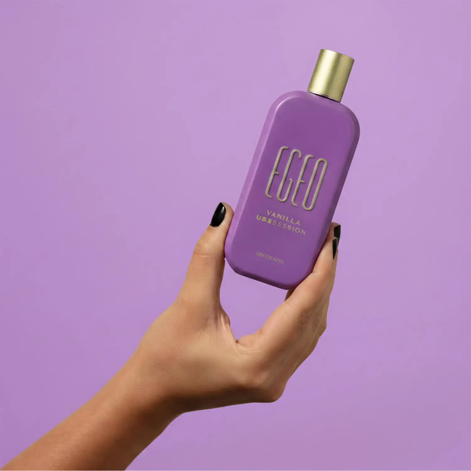 Frasco de item de perfumaria da marca Egeo em tom de roxo, com tampa dourada, segurado por mão feminina sobre fundo liso roxo.