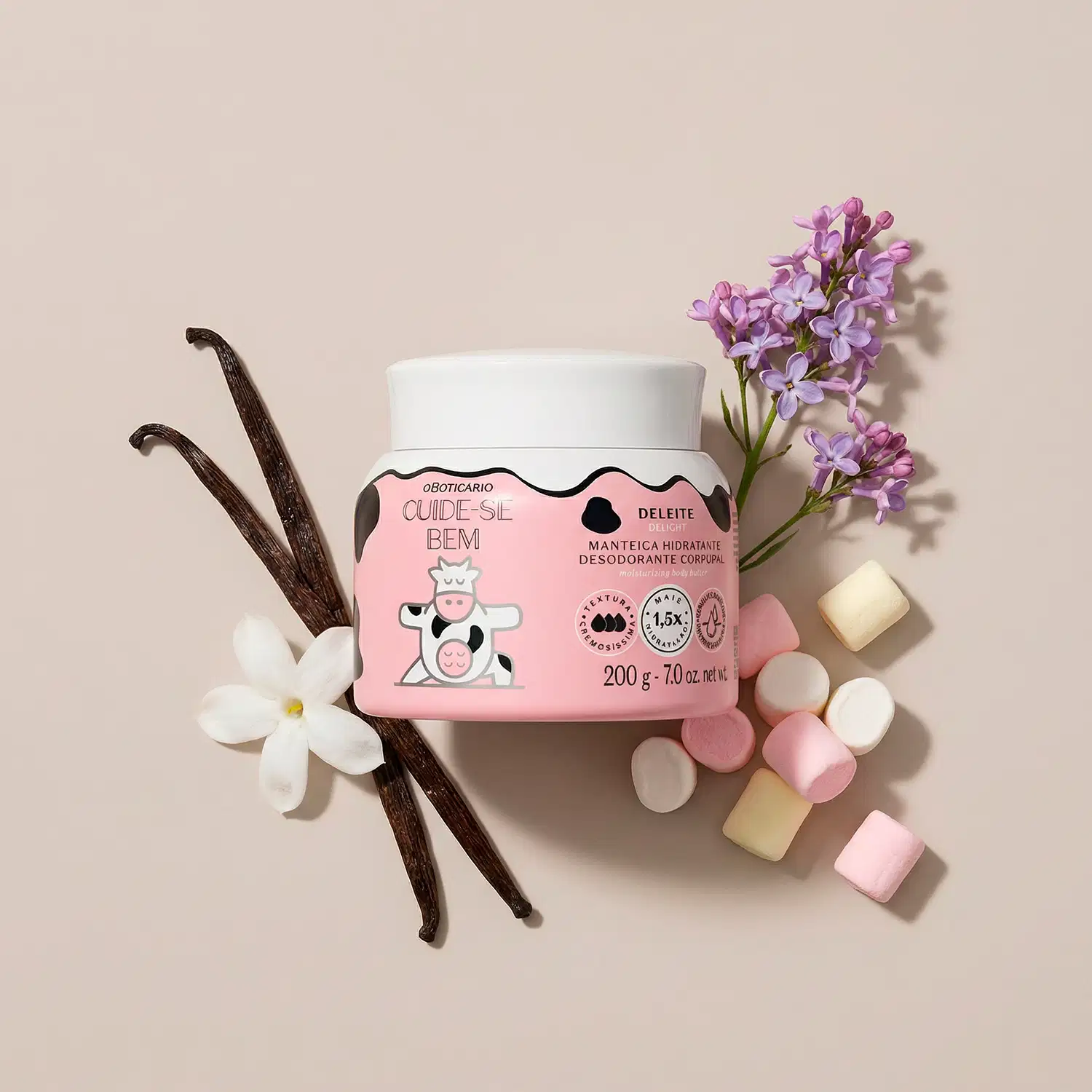A imagem mostra o recipiente branco de manteiga corporal Cuide-se Bem Deleite com rótulo rosa e ilustração de vaca. Ao redor, flores, favas de baunilha e marshmallows em fundo bege claro, sugerindo doçura e aconchego.